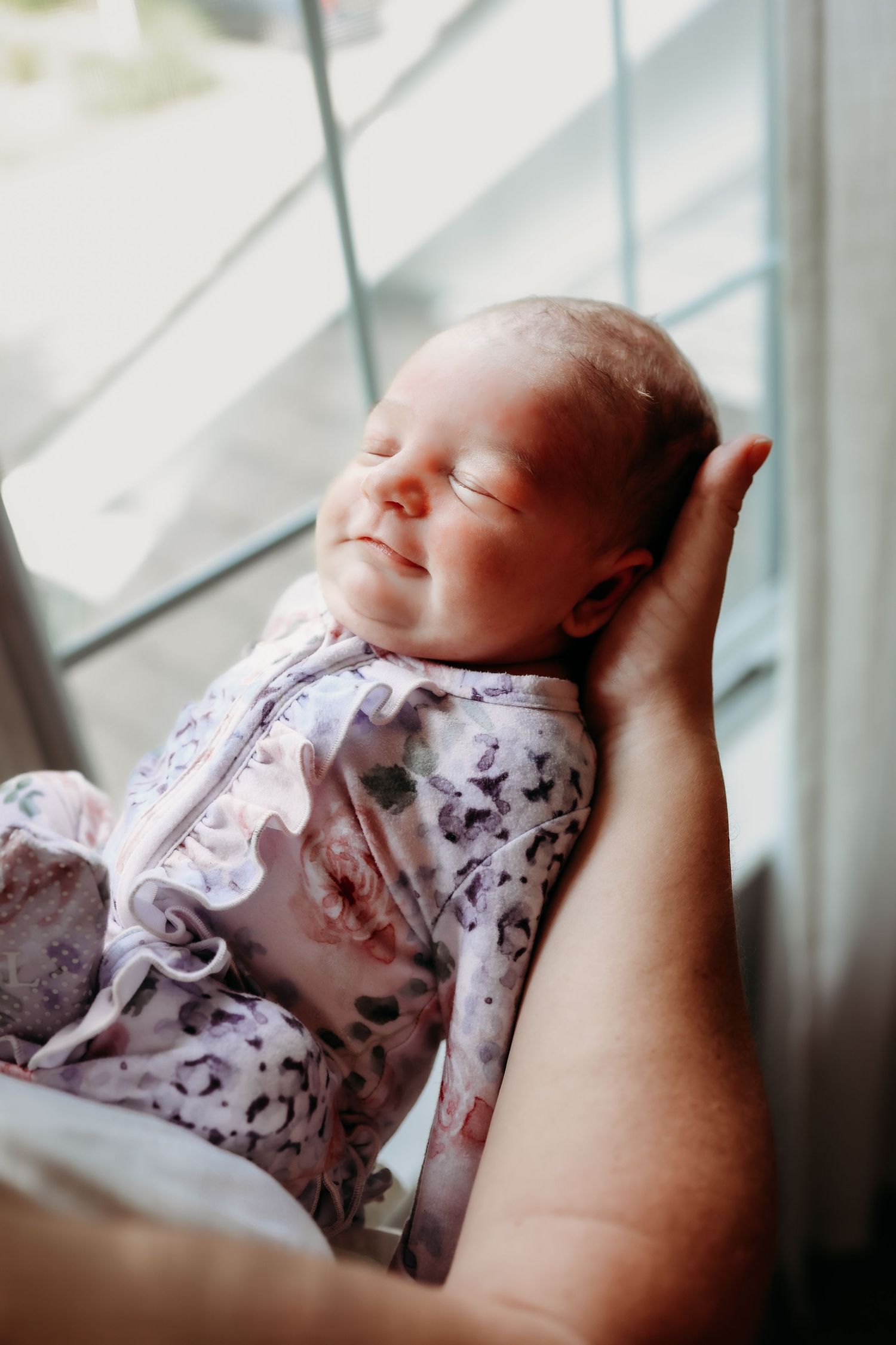 A series of four connected images showing a sleeping newborn baby in pink patterned clothing held in someone's arms.