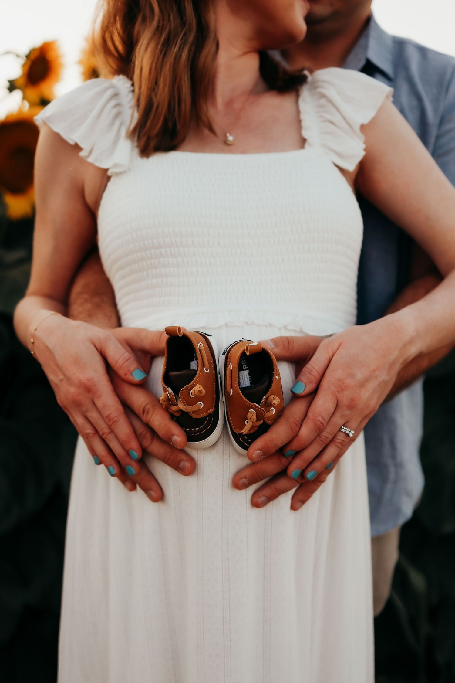 Close-up shots show hands holding baby shoes against a white dress at sunset in Andover, New Jersey maternity session.