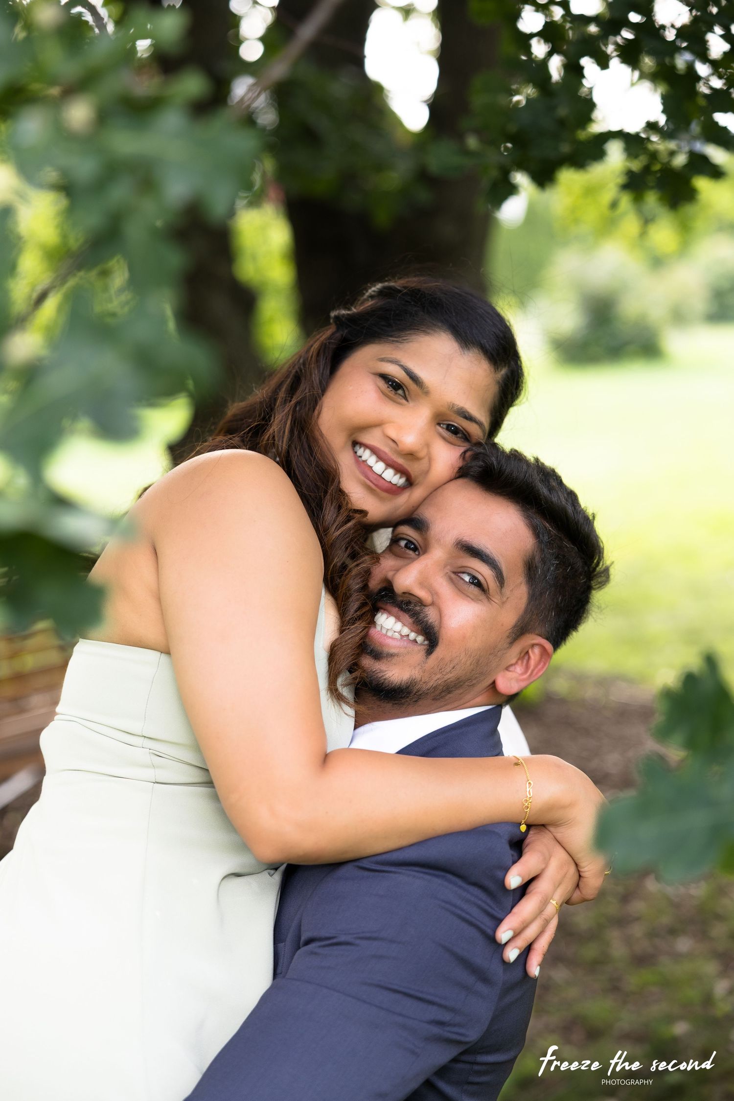 Joyful couple embracing outdoors, woman laughing while piggyback riding man in summer garden.
