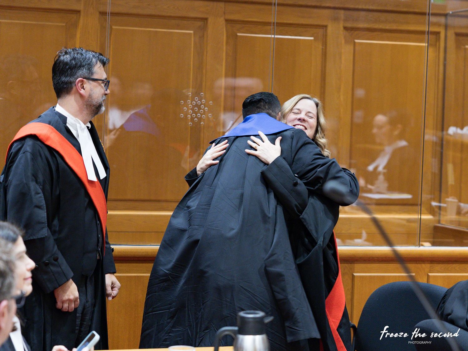 Newly called lawyer shares a warm embrace with a robed official during bar admission ceremony.