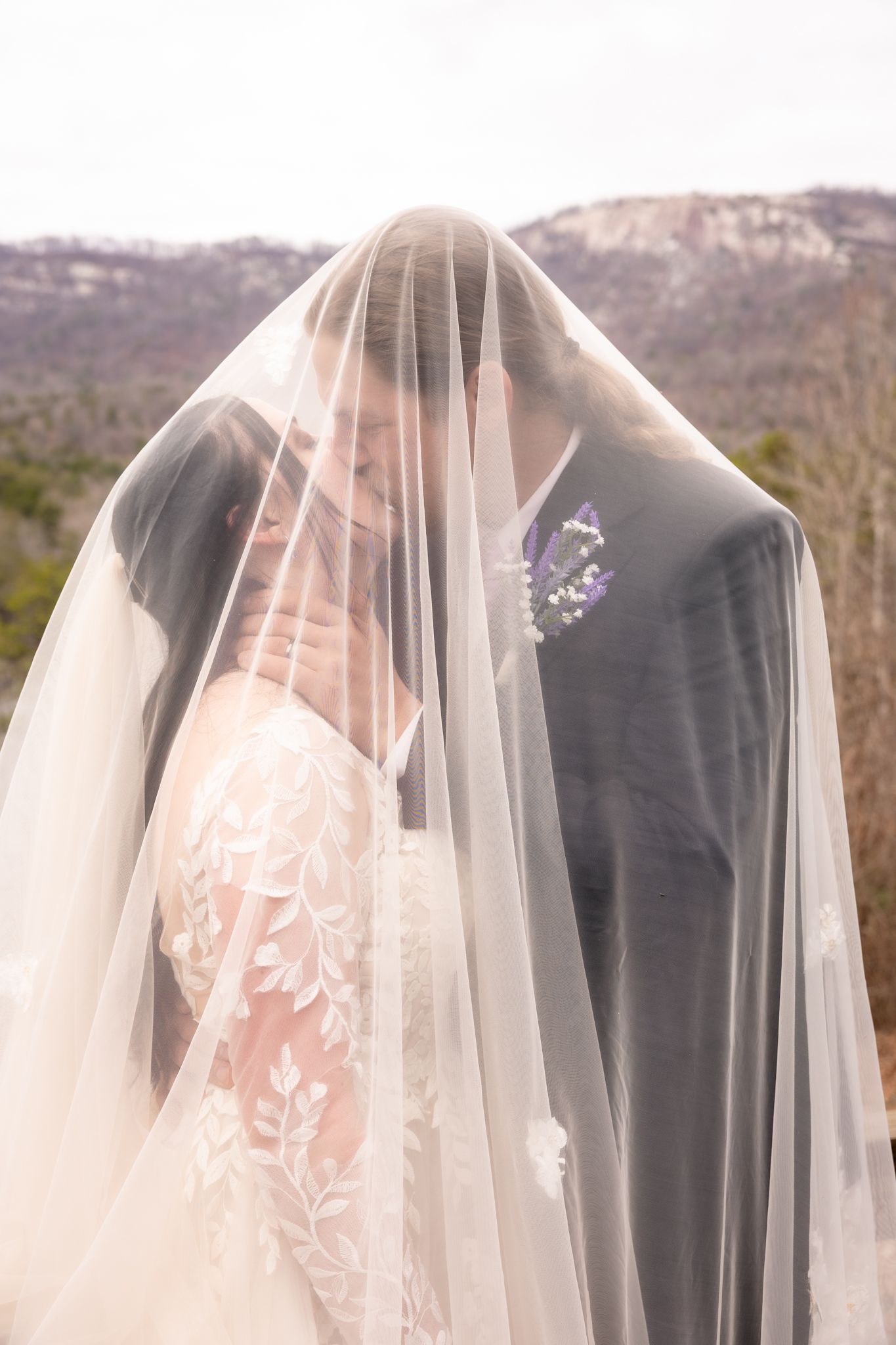 Romantic portrait of bride and groom sharing an intimate moment together under a flowing bridal veil outdoors at Table Rock State Park.