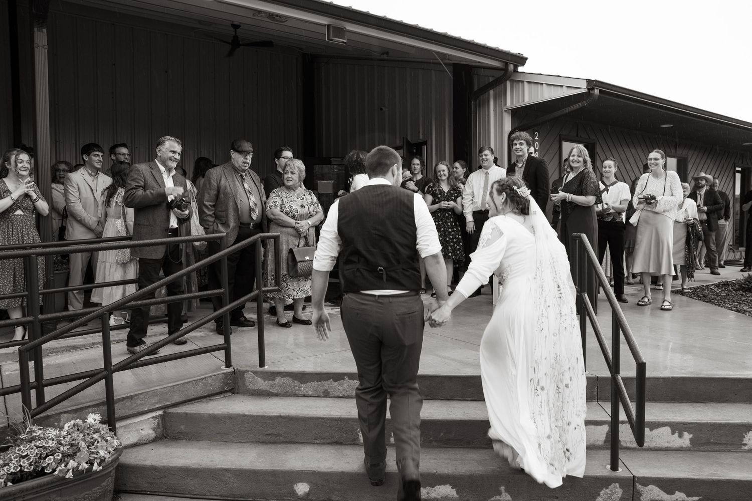 ©AnnaVonRiesenPhotography Wedding Photography | B&W image of the bride & groom walking into their reception venue being cheered by guests.