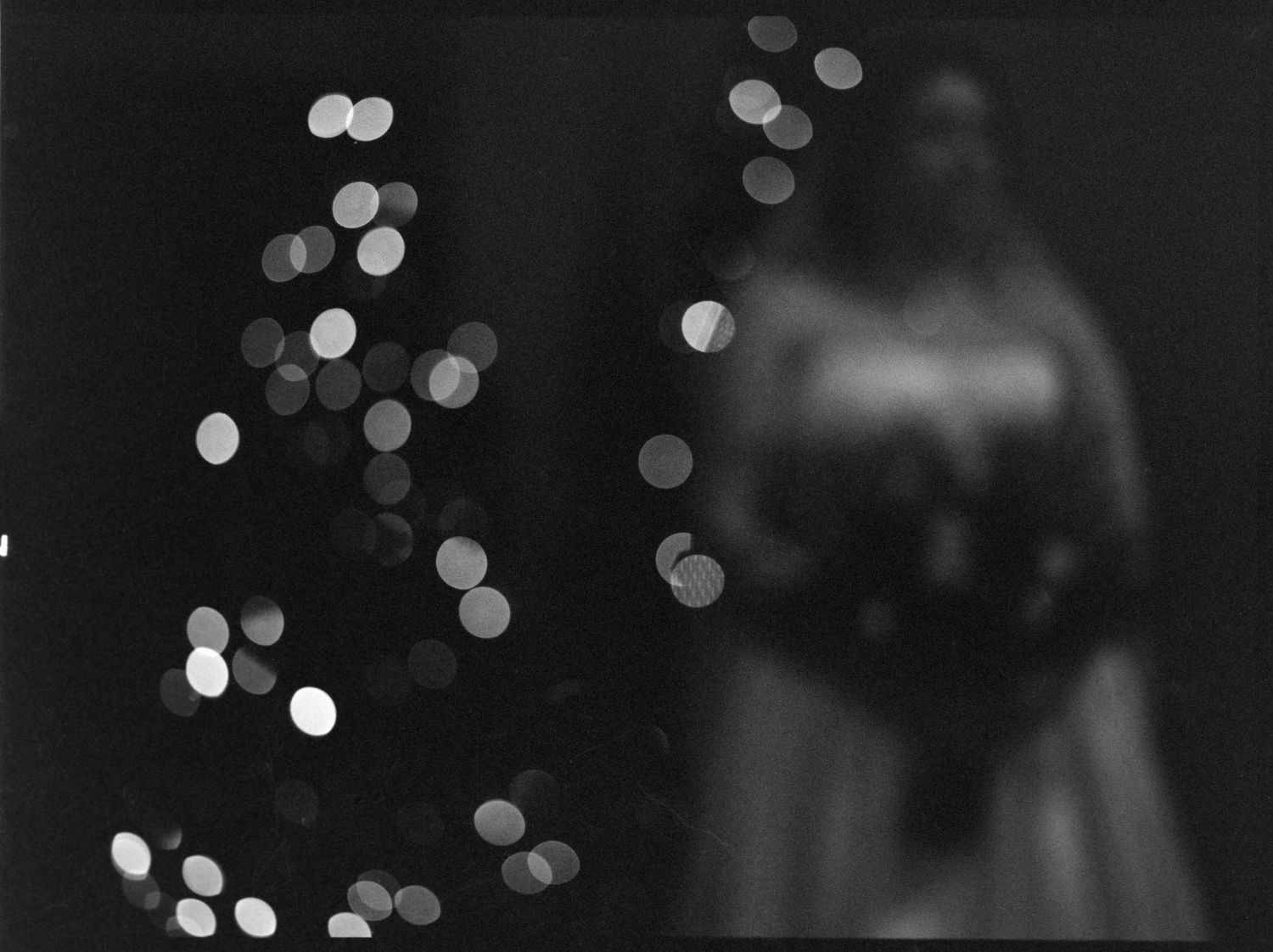 ©AnnaVonRiesenPhotography Wedding Photography | B&W out of focus image of a bride standing in front of christmas lights.