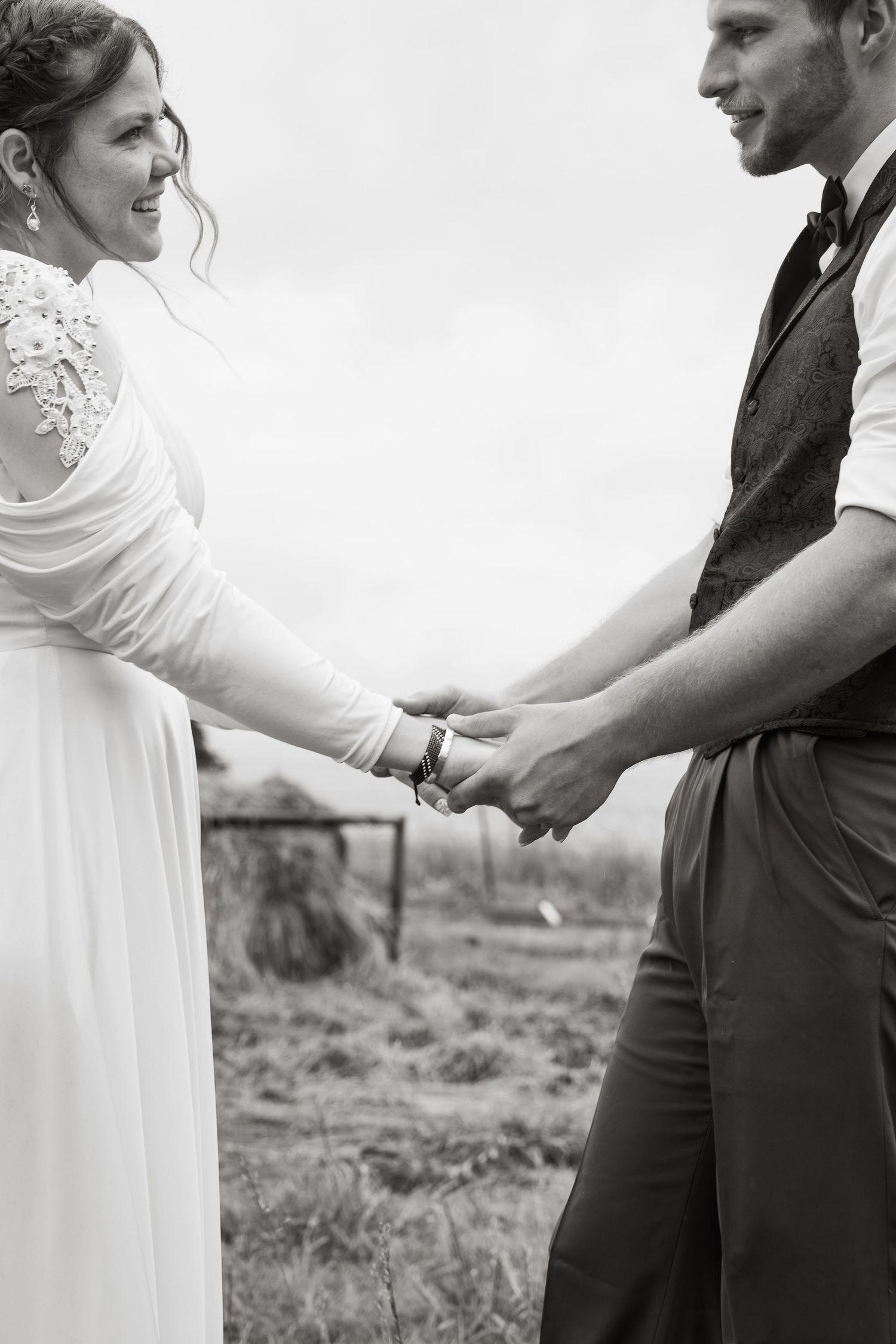©AnnaVonRiesenPhotography Wedding Photography | B&W image of the bride & groom holding hands & smiling at each other.