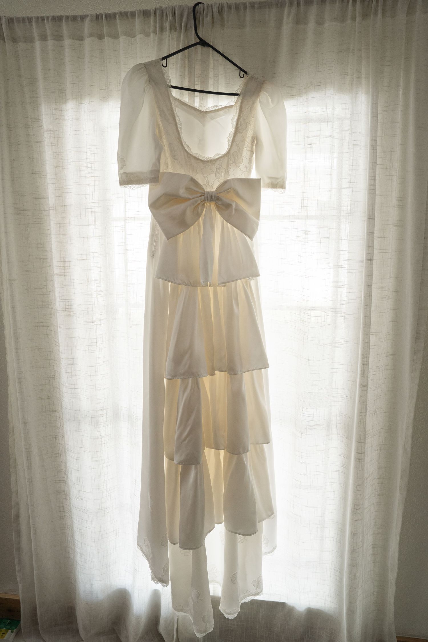 ©AnnaVonRiesenPhotography Wedding Photography | Color image of the wedding dress hanging in a window.