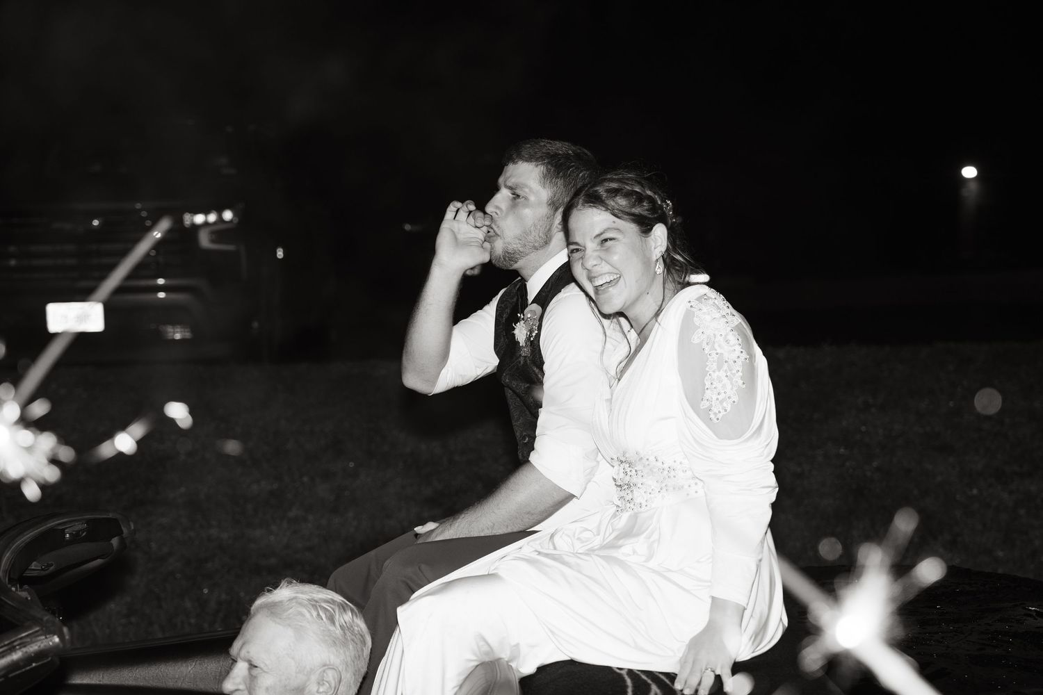 ©AnnaVonRiesenPhotography Wedding Photography | B&W image of a bride & groom smiling on the back of their getaway car.