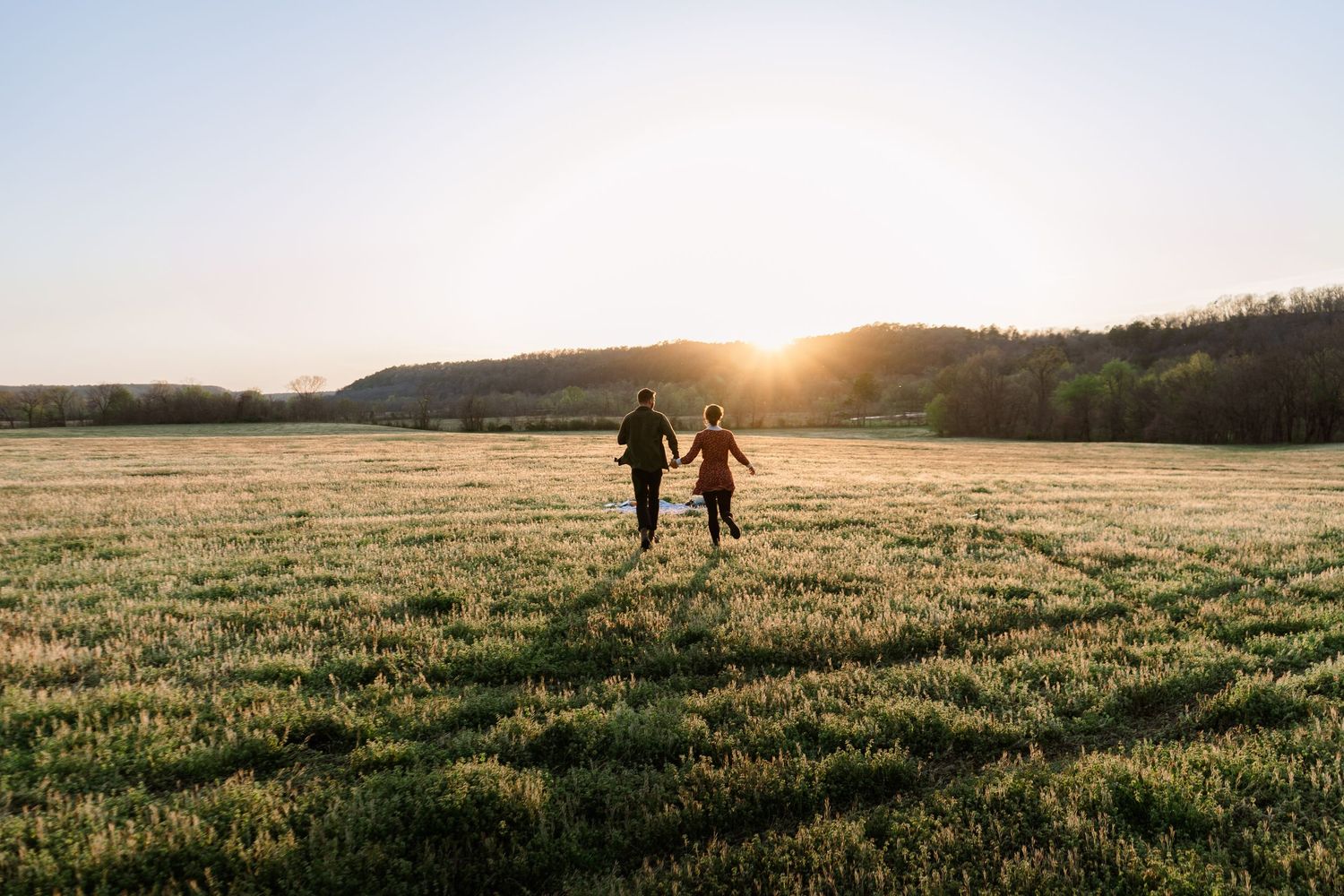 ©AnnaVonRiesenPhotography Couples Photography | Color image of a couple running towards the sunset while holding hands.