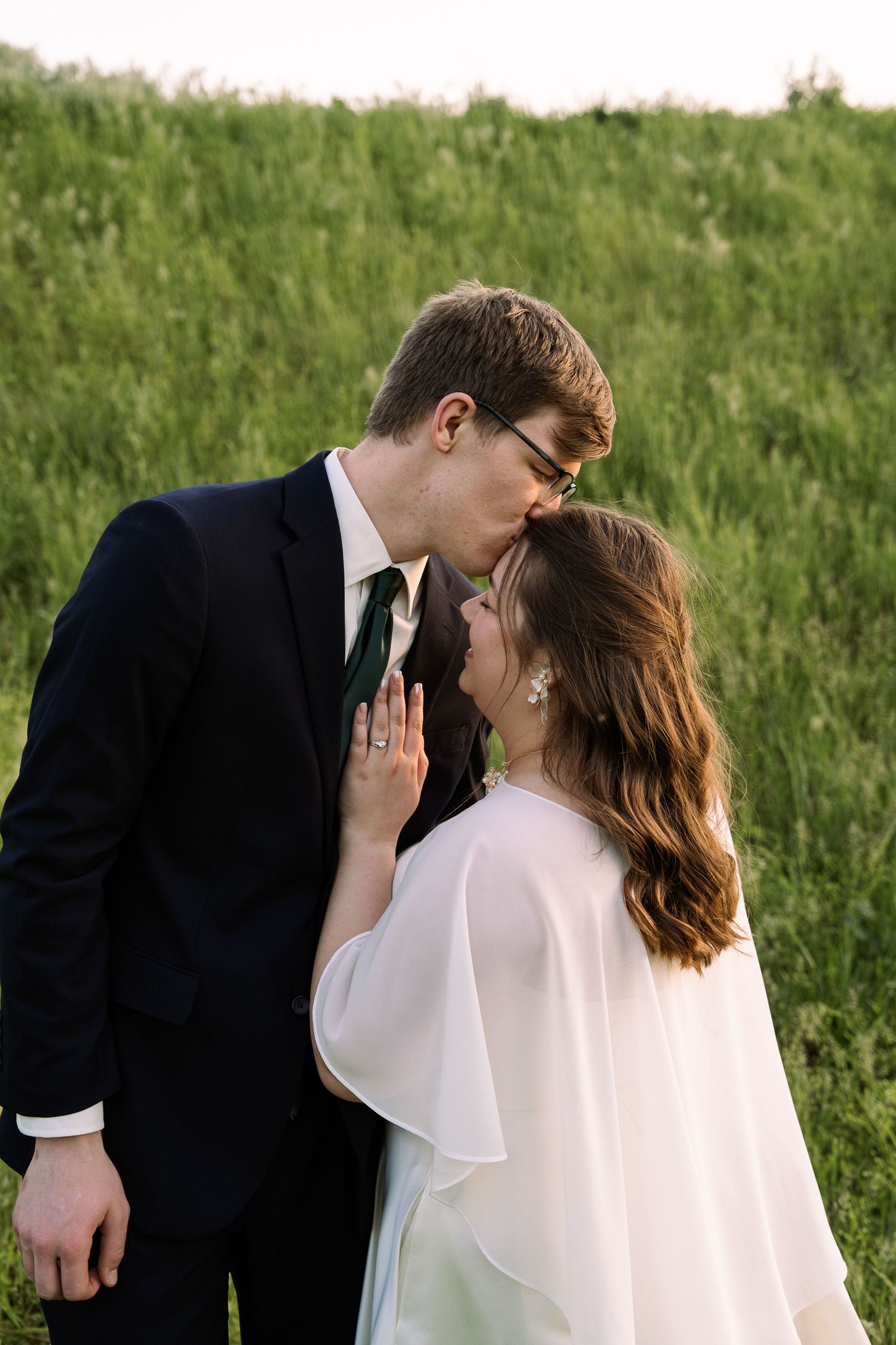 ©AnnaVonRiesenPhotography Wedding Photography | Color image of a groom kissing his bride on the foreheard.