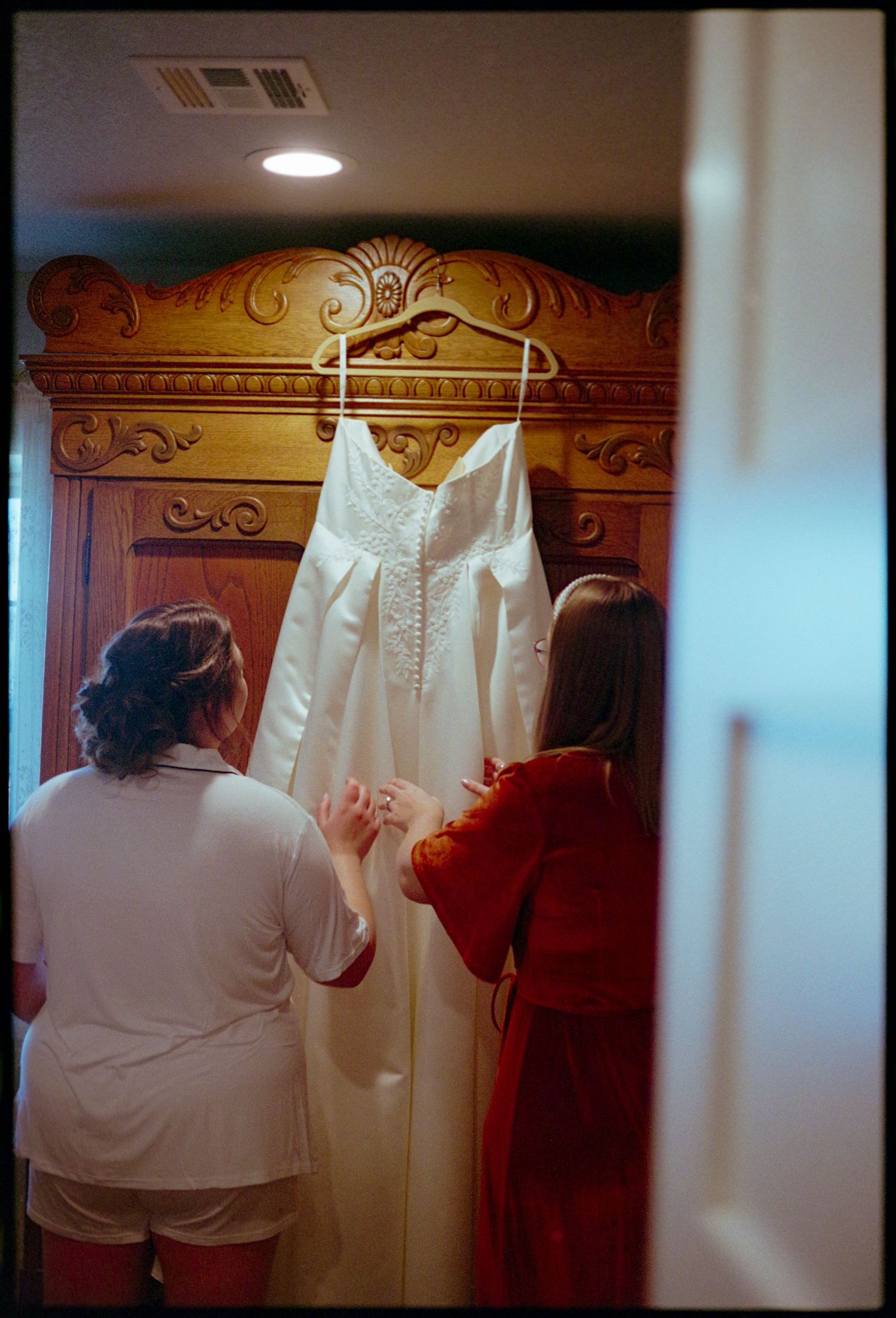 ©AnnaVonRiesenPhotography Wedding Photography | Film Color image of the bride & her friend admiring the wedding dress.