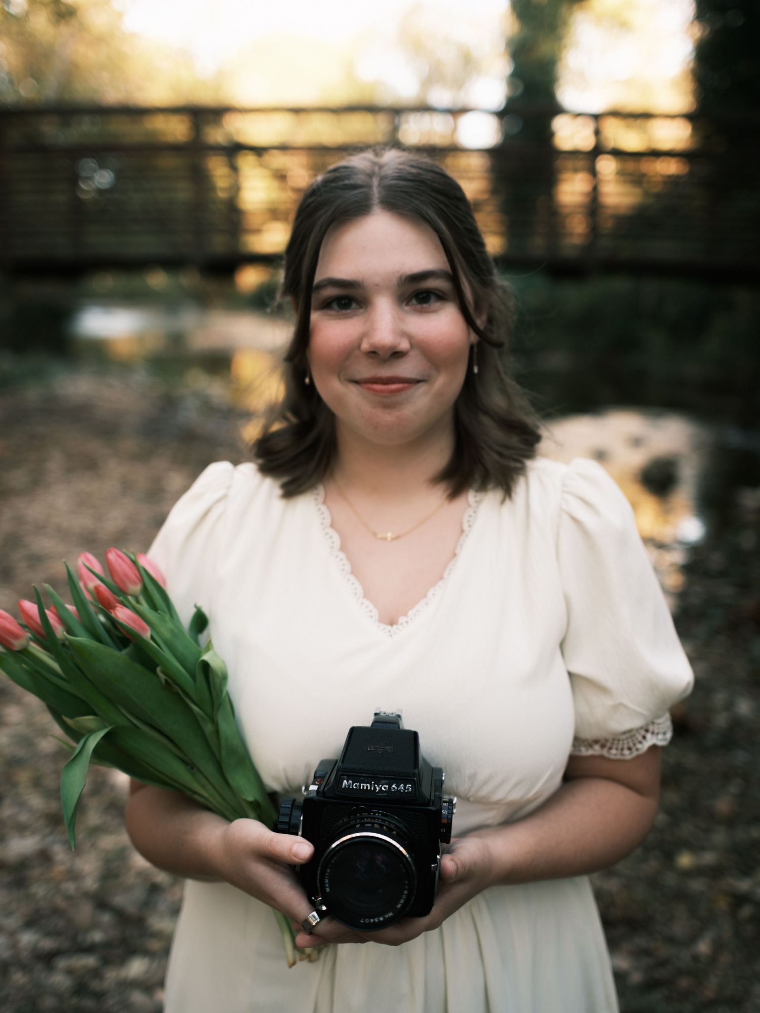 ©Stone Robinson | Portrait of Anna VonRiesen smiling while holding a film camera & a bundle of tulips.