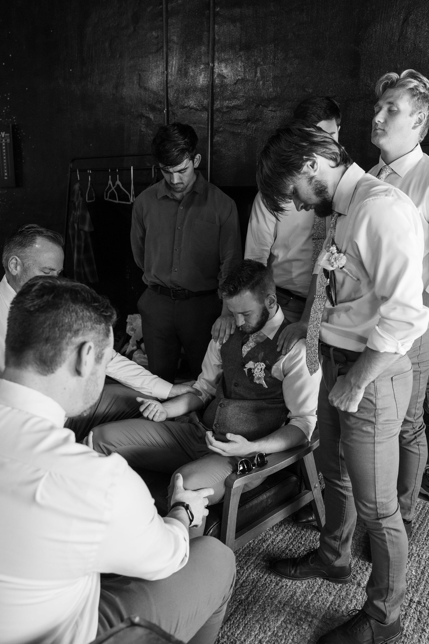 ©AnnaVonRiesenPhotography Wedding Photography | B&W image of the groomsmen praying over the groom.