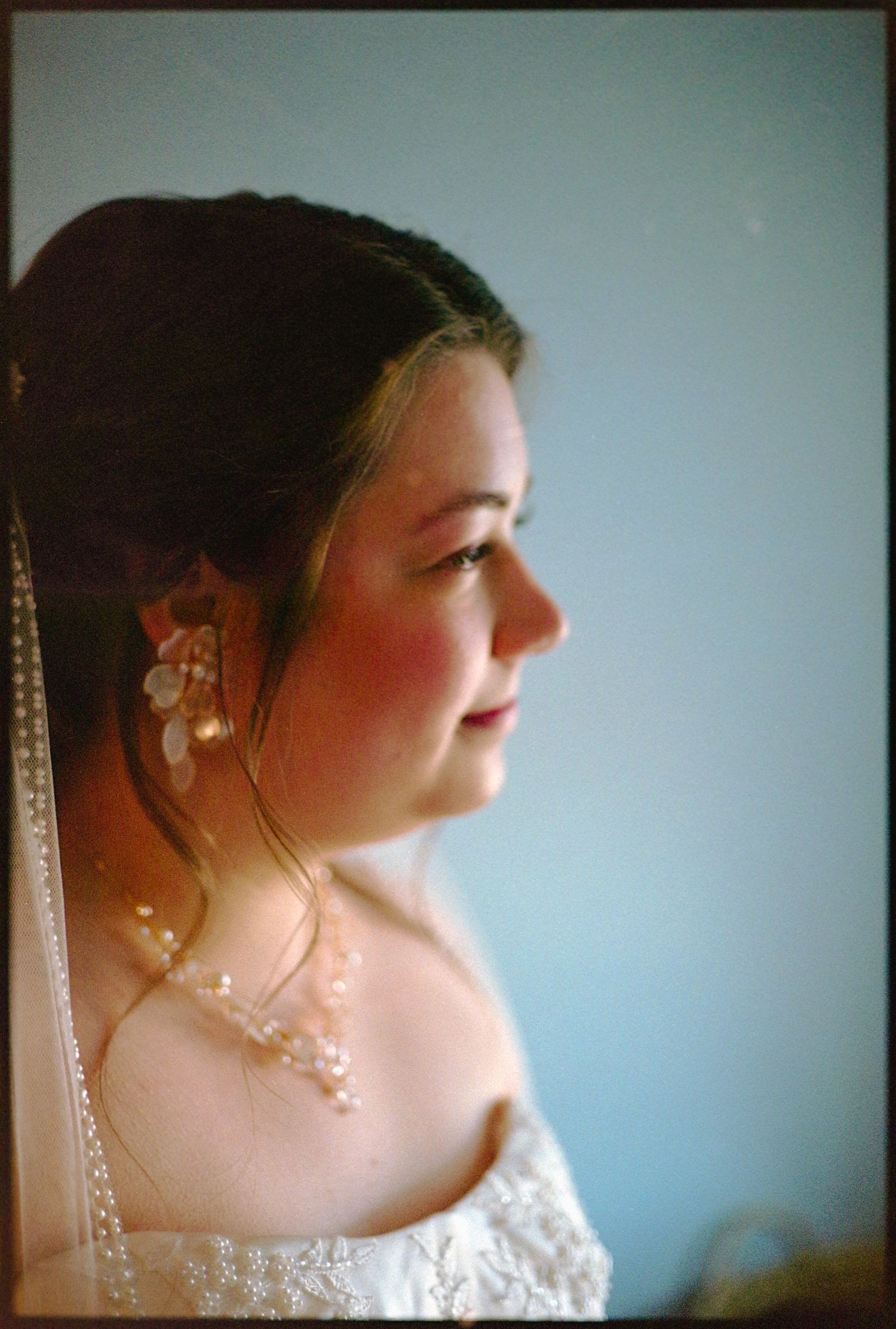 ©AnnaVonRiesenPhotography Wedding Photography | Film Color image of the bride looking out a window.