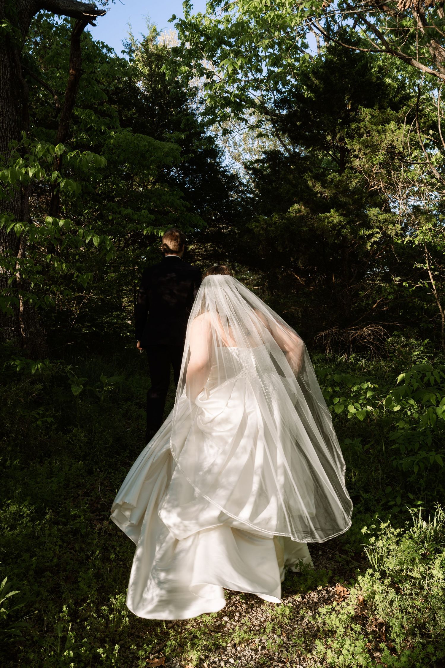©AnnaVonRiesenPhotography Wedding Photography | Color image of the groom leading his bride down a path.
