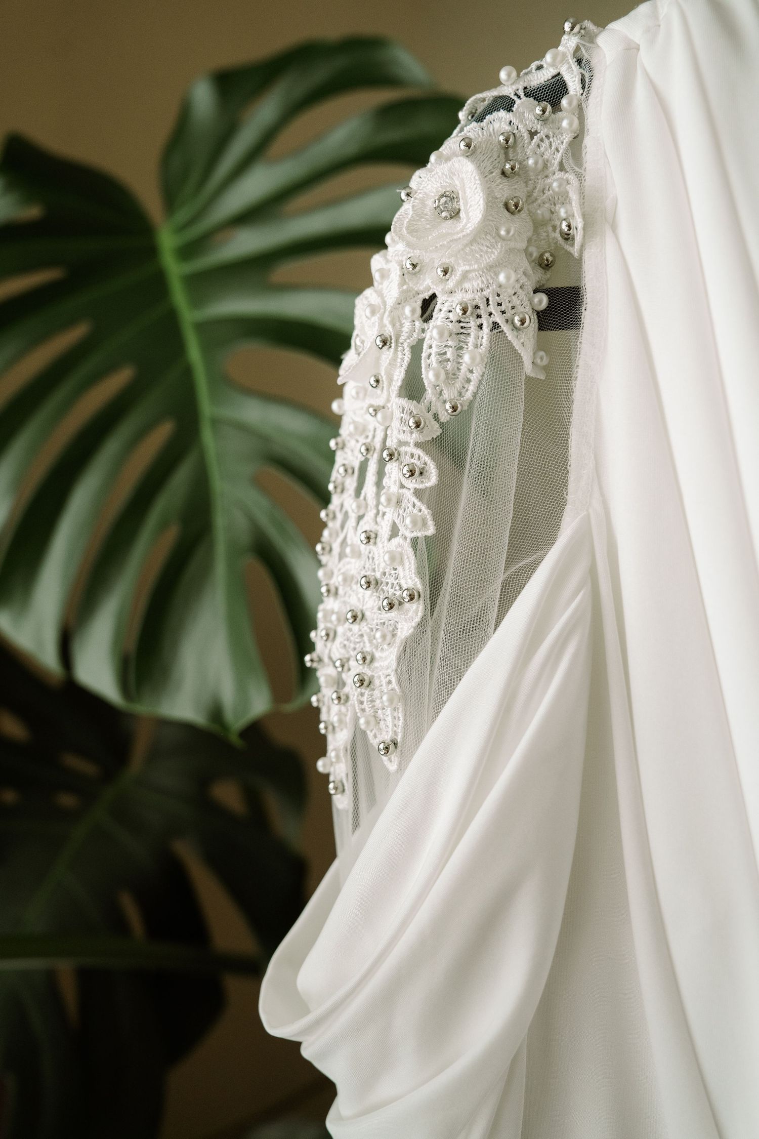 ©AnnaVonRiesenPhotography Wedding Photography | Color image of a dress sleeve against a palm plant.