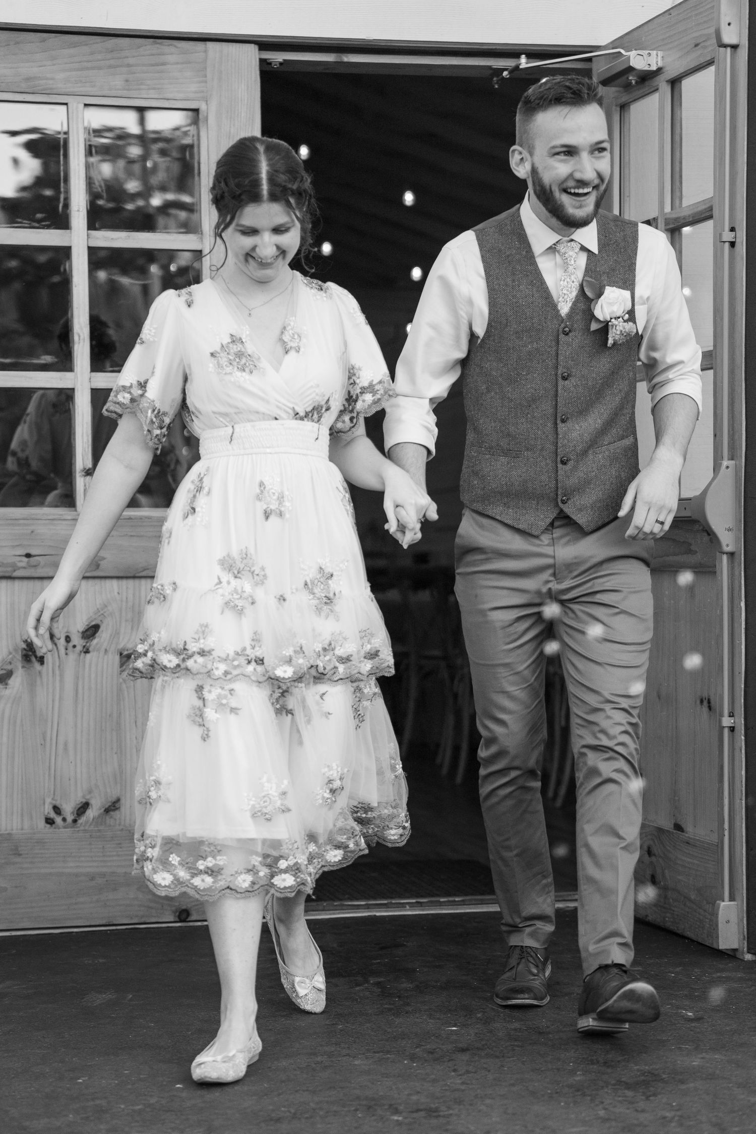 ©AnnaVonRiesenPhotography Wedding Photography | B&W image of a bride & groom holding hands as they exit their venue.