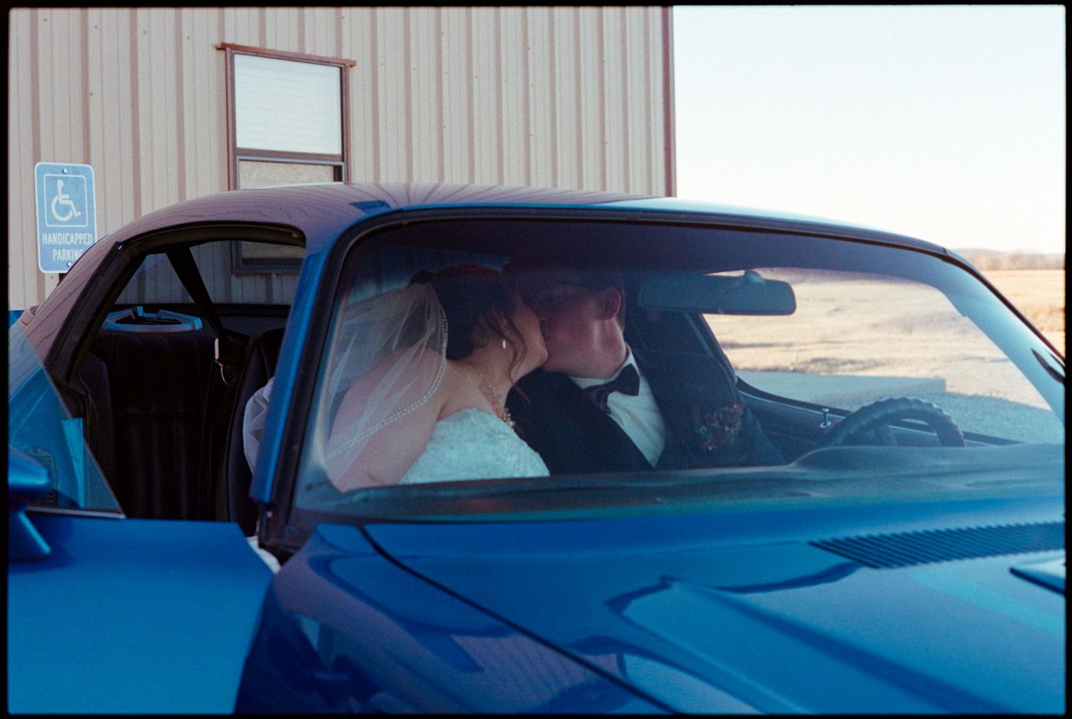 ©AnnaVonRiesenPhotography Wedding Photography | Film Color image of the bride & groom kissing through the window of a cool car.