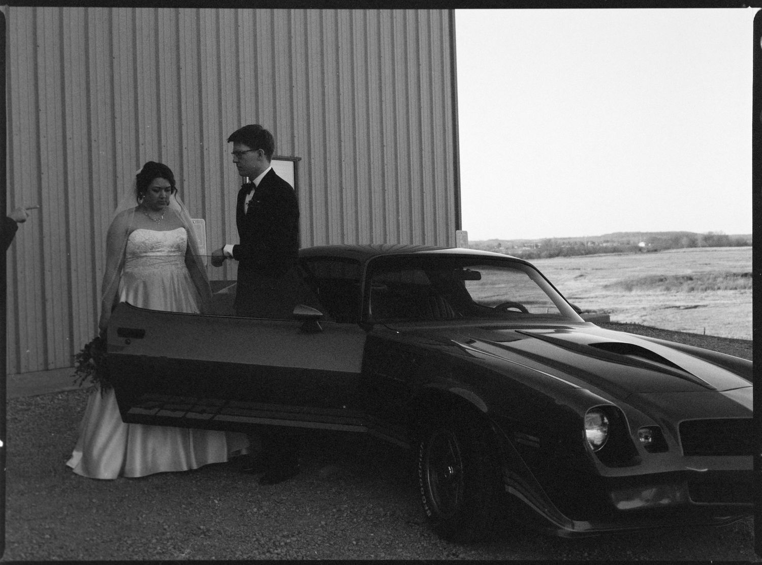 ©AnnaVonRiesenPhotography Wedding Photography | Film B&W image of the bride & groom posing by a cool car.