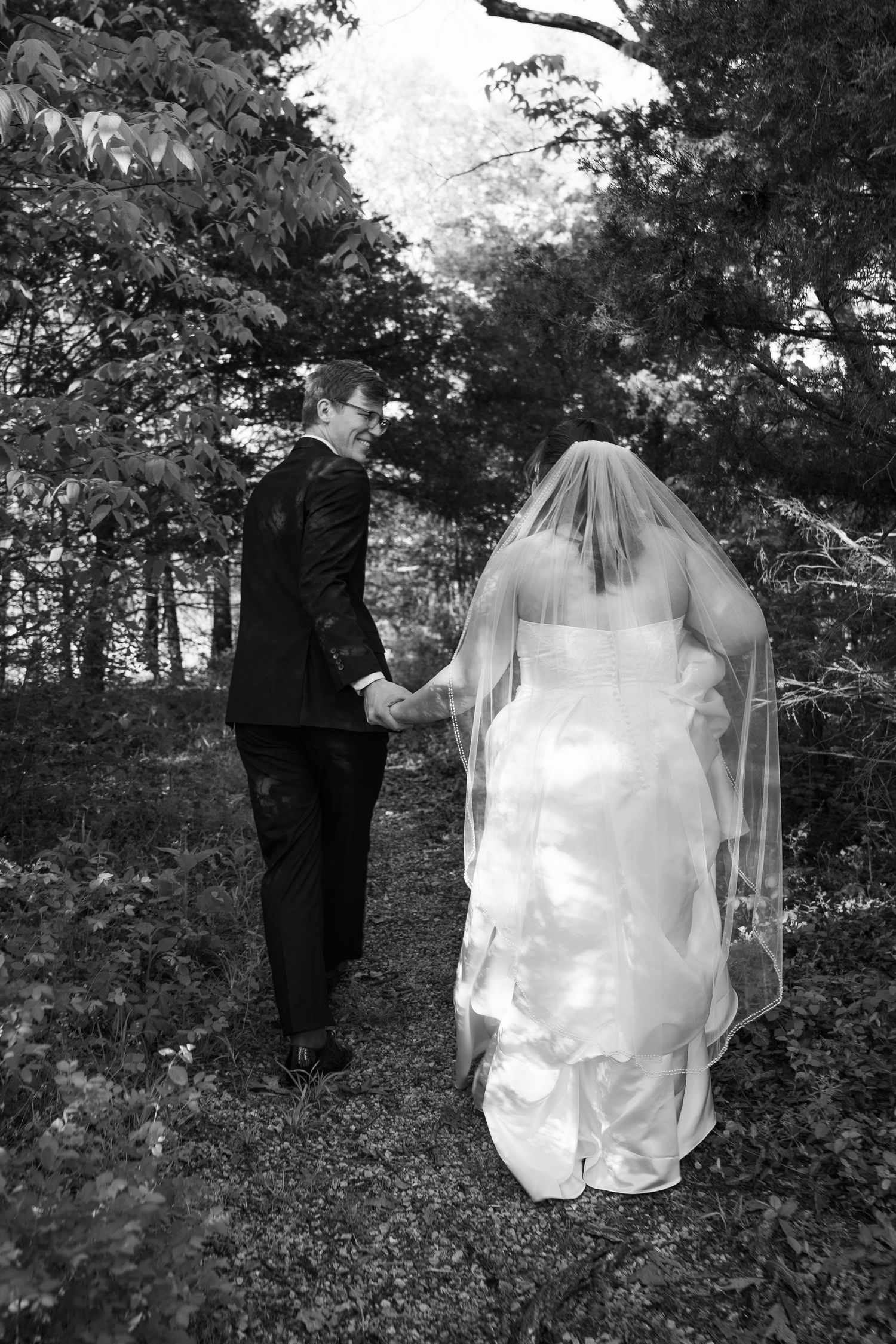 ©AnnaVonRiesenPhotography Wedding Photography | B&W image of a bride and groom walking through a forest.