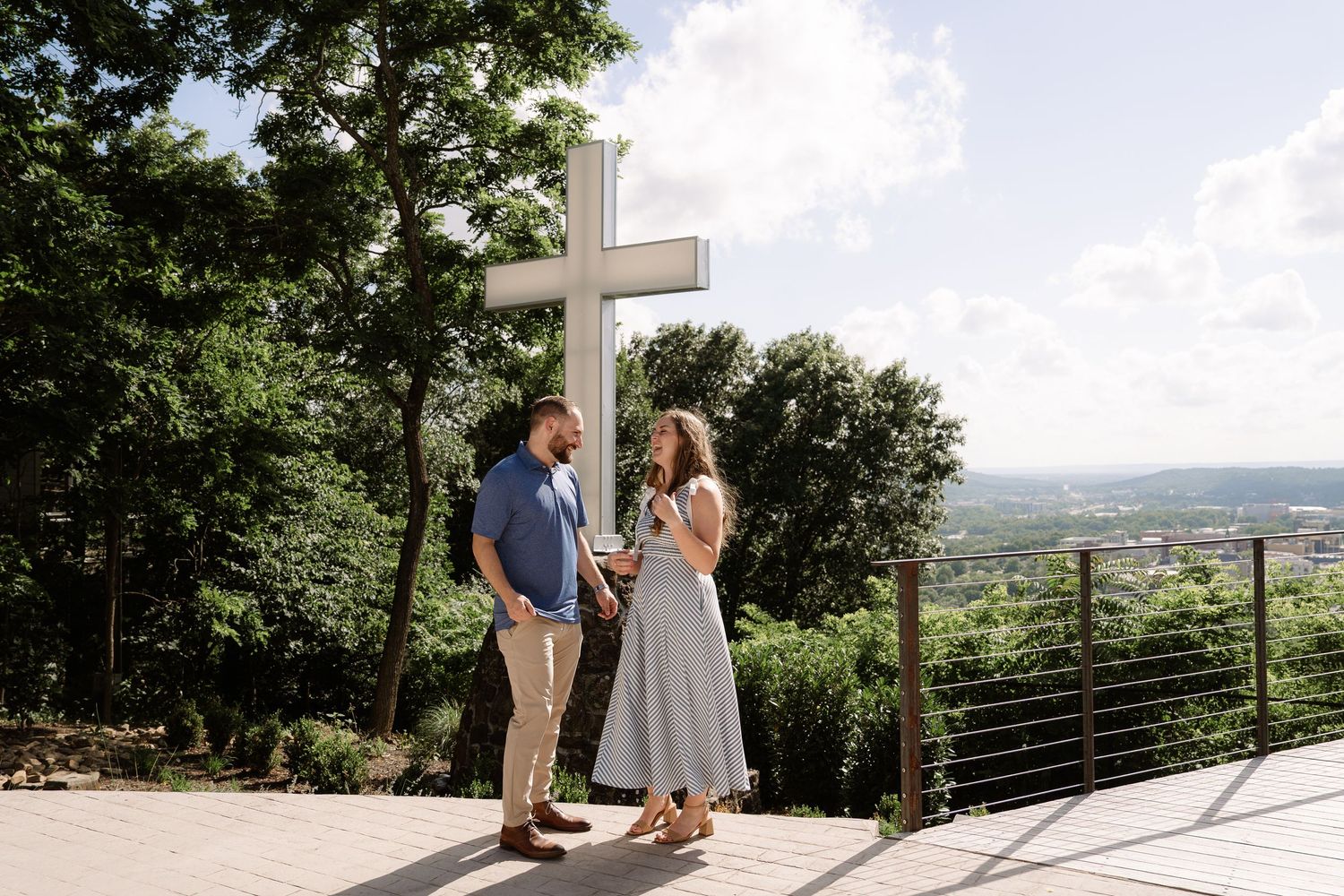 ©AnnaVonRiesenPhotography Engagement Photography | Color image of a couple standing in front of a cross overlooking the city.