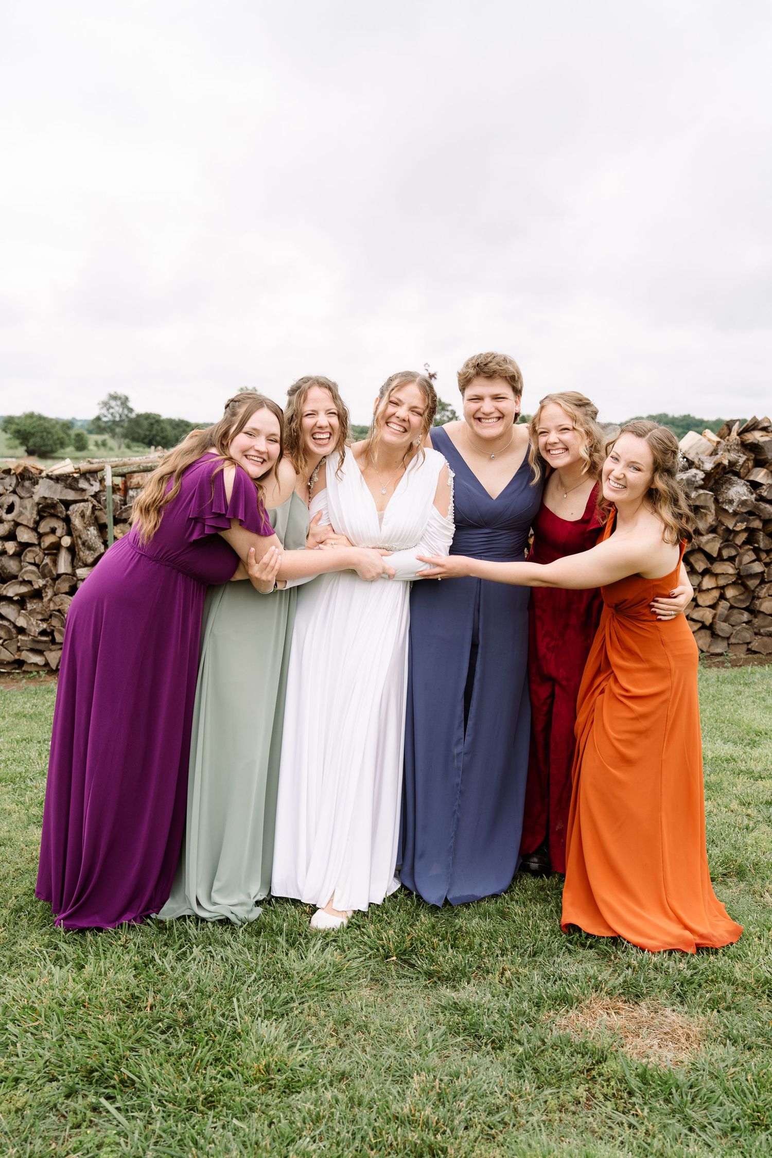 ©AnnaVonRiesenPhotography Wedding Photography | Color image of the bride smiling & hugging her bridesmaids.