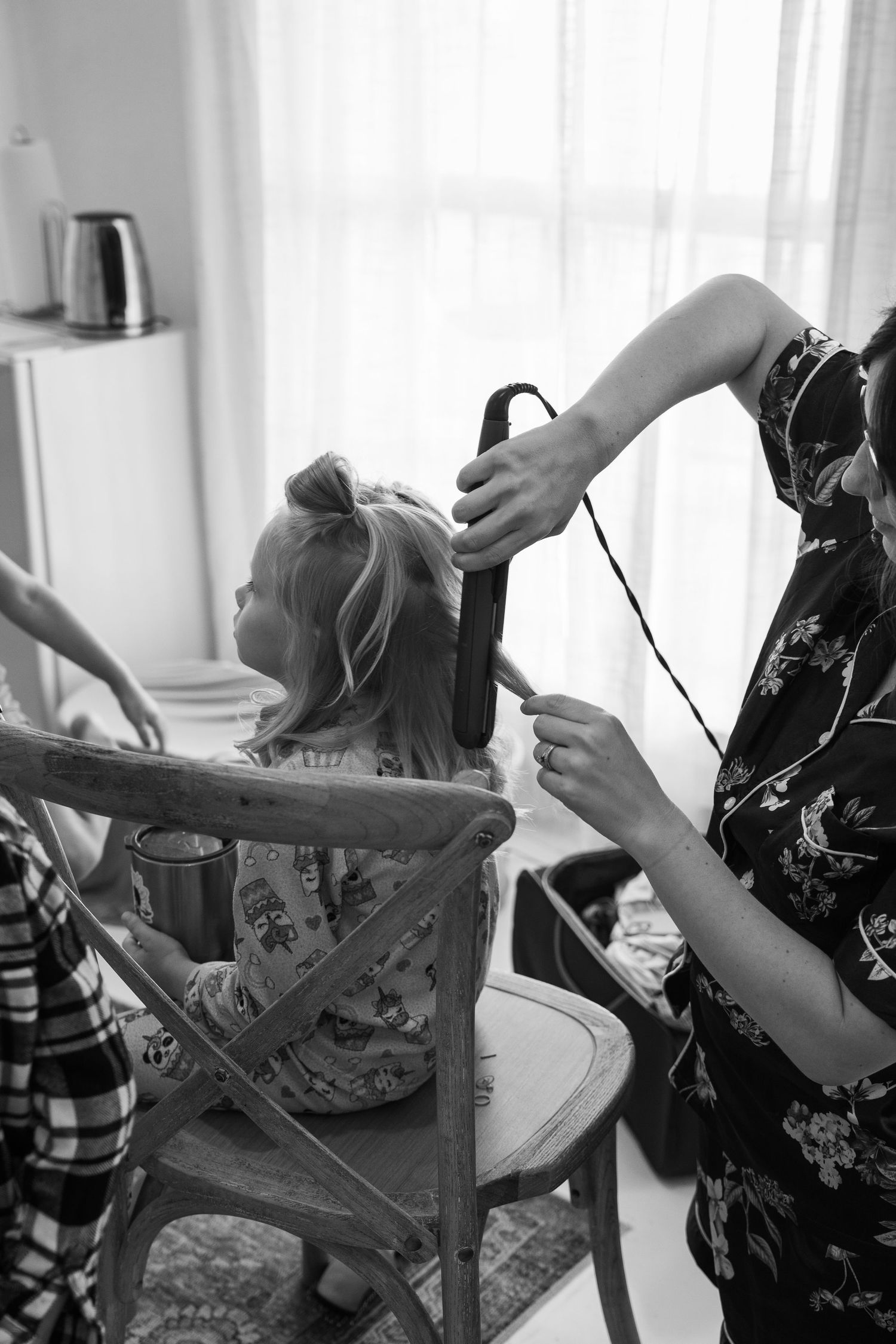 ©AnnaVonRiesenPhotography Wedding Photography | B&W image of a woman curling a flower girl's hair.