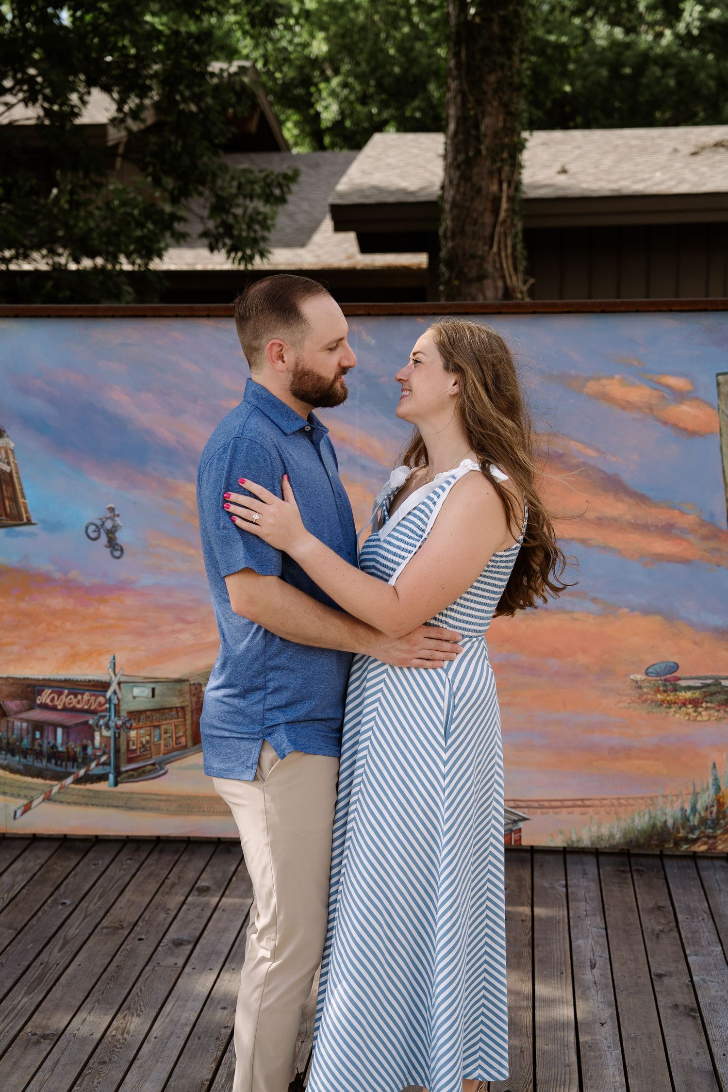 ©AnnaVonRiesenPhotography Engagement Photography | Color image of a couple holding each other in front of a mural & smiling.