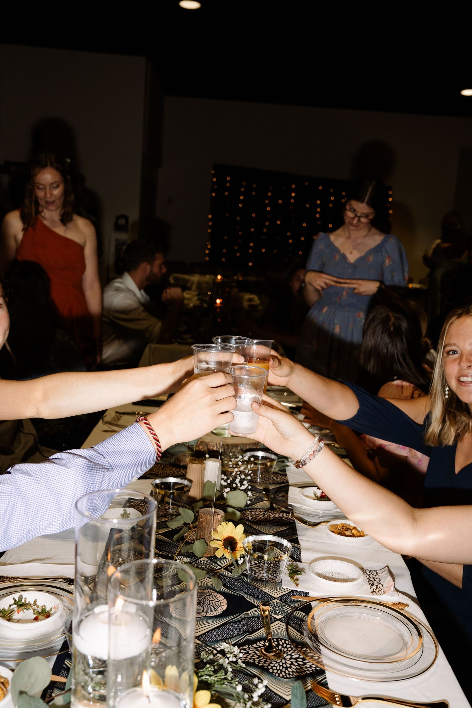 ©AnnaVonRiesenPhotography Wedding Photography | Color image of wedding guests raising their glasses in the middle of the table.