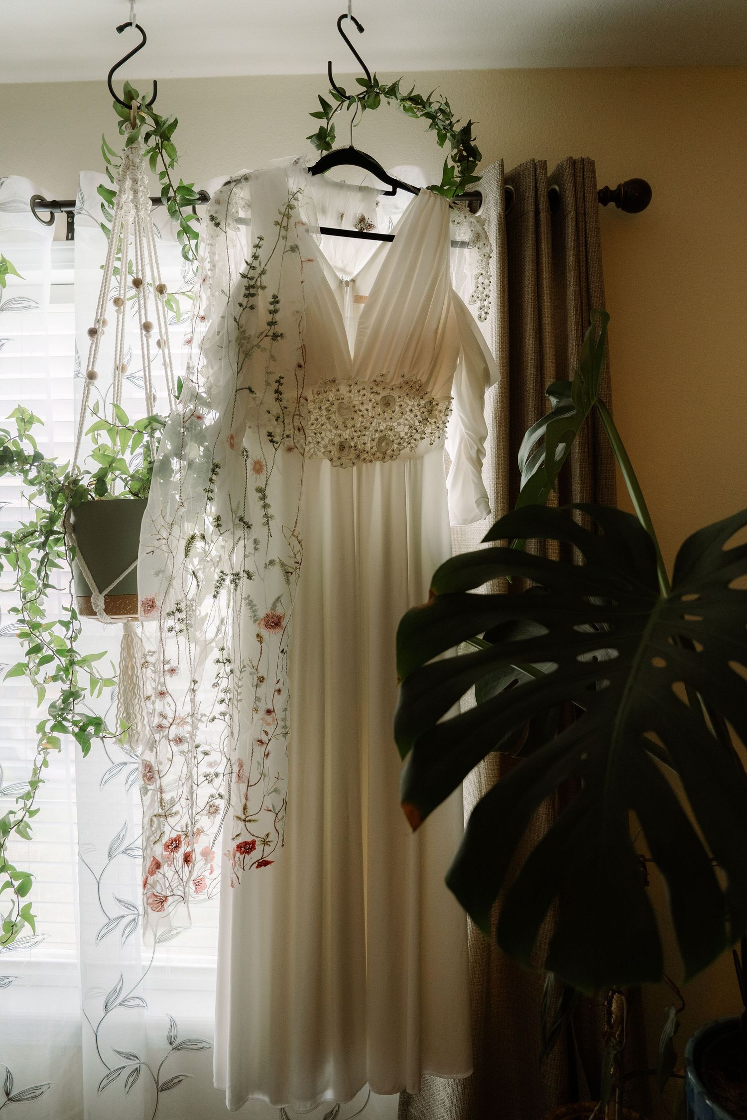 ©AnnaVonRiesenPhotography Wedding Photography | Color image of the dress hanging in a window surrounded by plants.