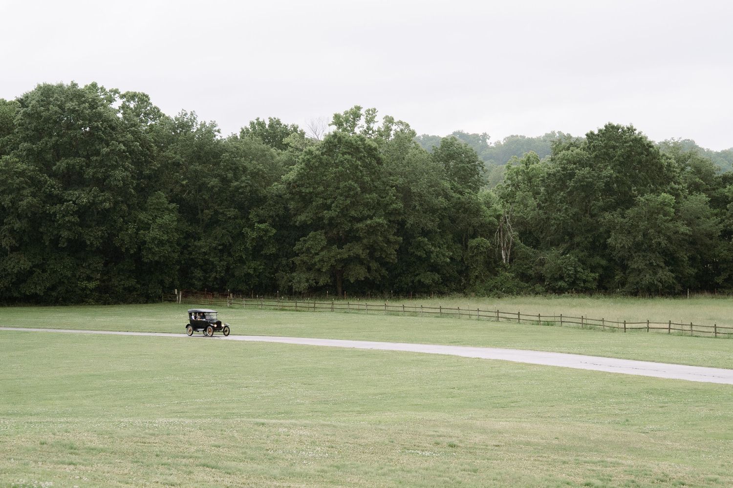 ©AnnaVonRiesenPhotography Wedding Photography | Color image of the bride and groom arriving by an old car across the green landscape.