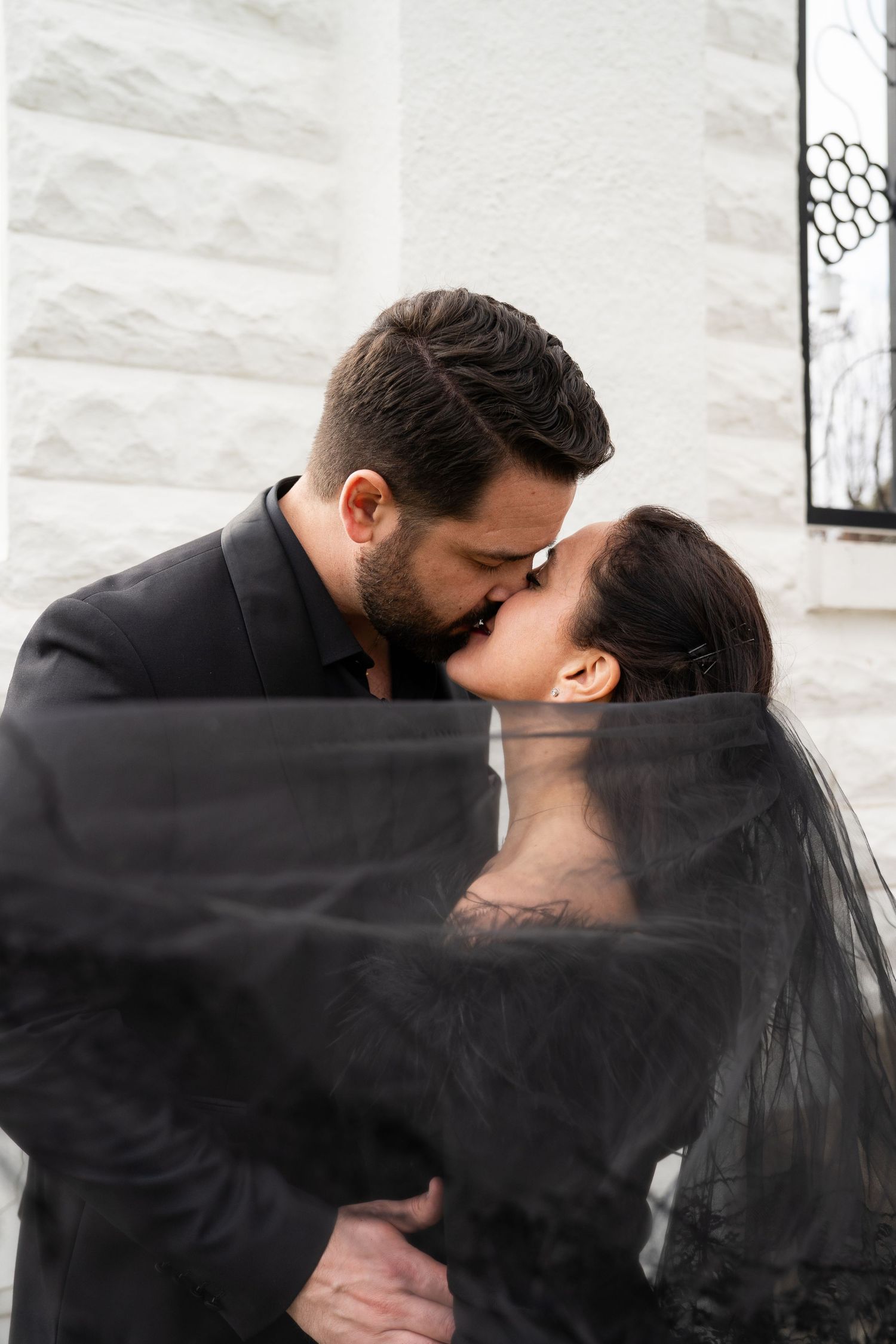 ©AnnaVonRiesenPhotography Wedding Photography | Color image of a bride & groom kissing with the veil pulled dramatically to the side.
