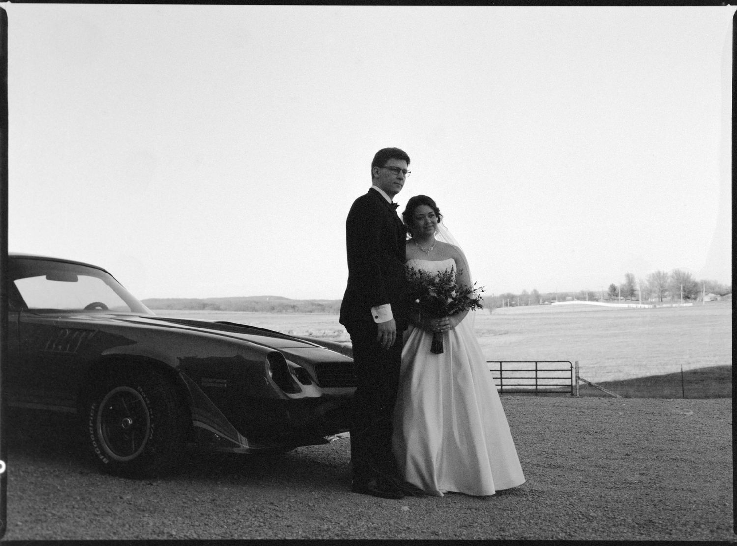 ©AnnaVonRiesenPhotography Wedding Photography | Film B&W image of the bride & groom posing by a cool car.