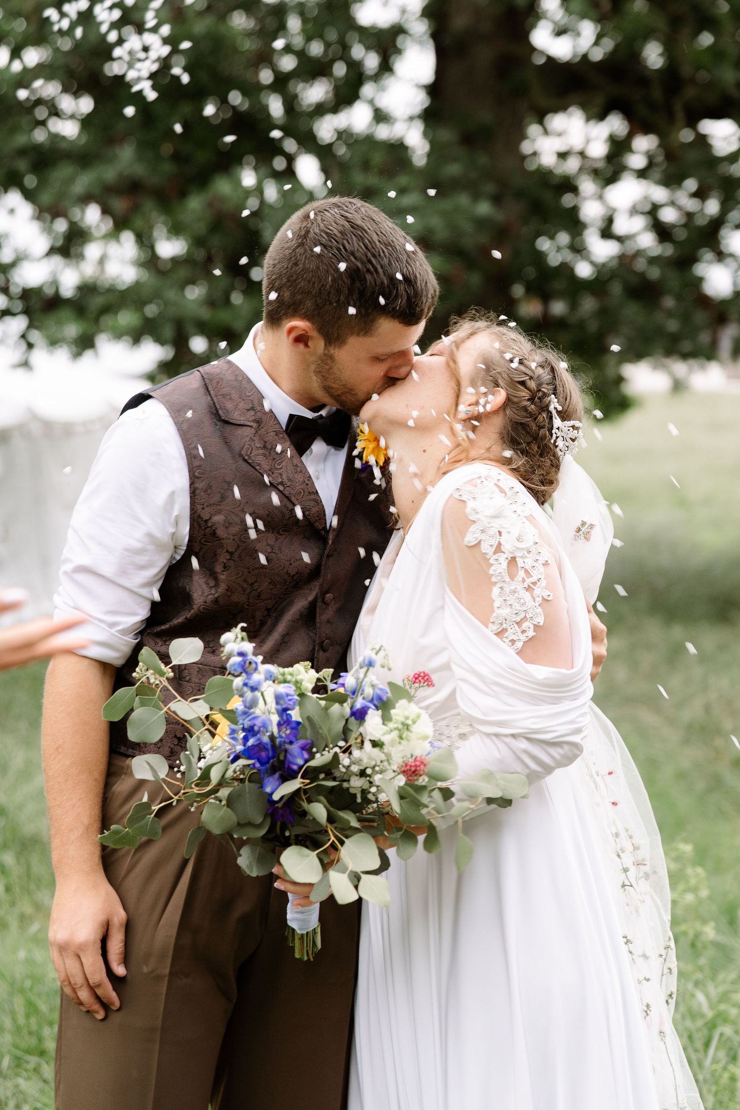 ©AnnaVonRiesenPhotography Wedding Photography | Color image of the bride & kissing while wedding rice is thrown on them.