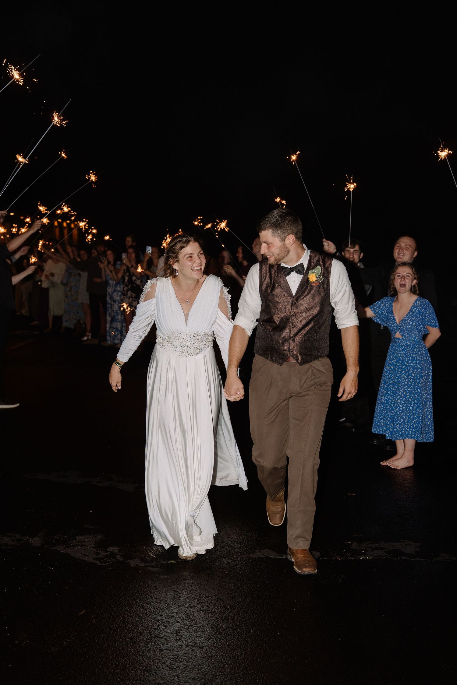 ©AnnaVonRiesenPhotography Wedding Photography | Color image of the bride & groom running through an aisle of people holding sparklers.