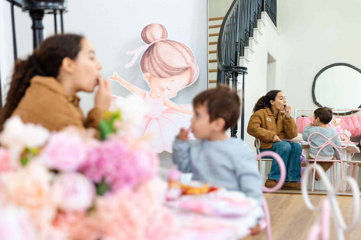 Children and adults gathered at a pink ballerina-themed birthday party with floral decorations.
