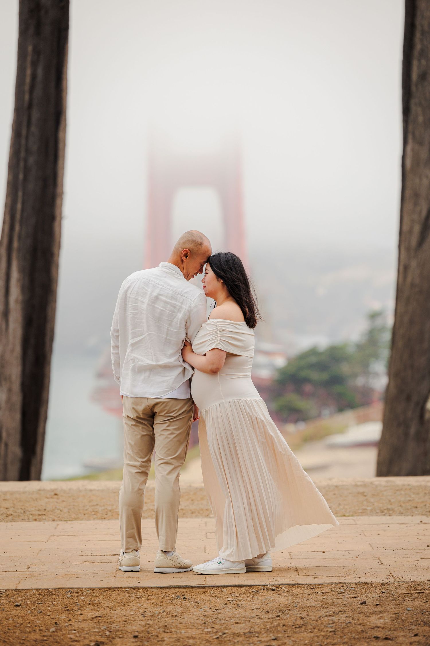 Couple embracing in front of the foggy Golden Gate Bridge in San Francisco.