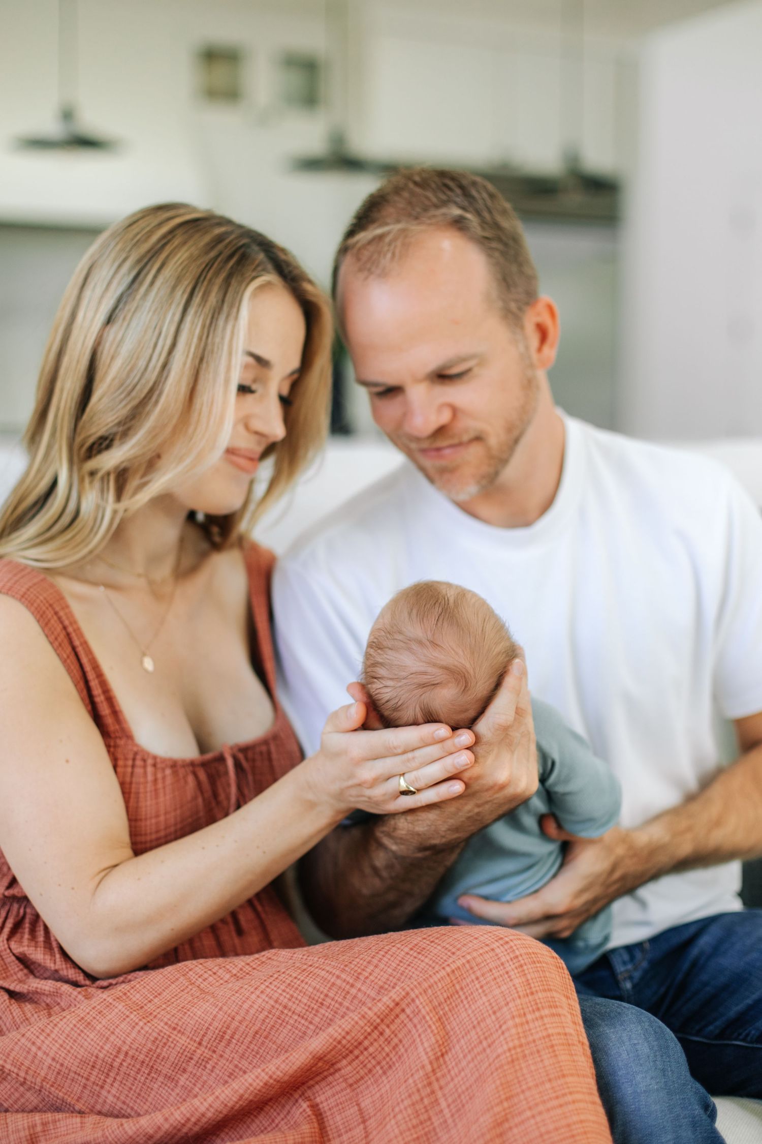 Loving parents tenderly cradling their newborn baby together in a bright, modern home setting.