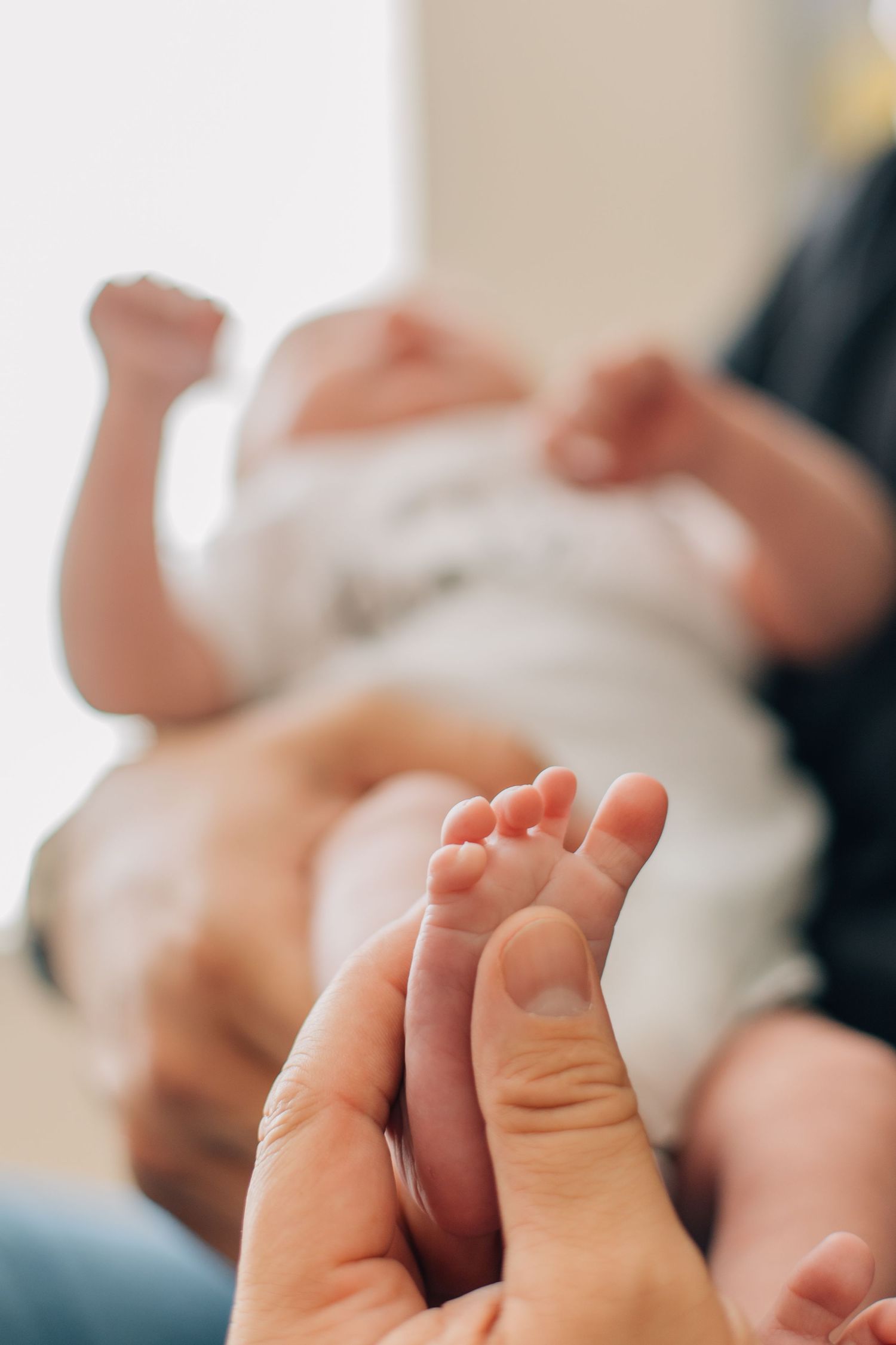 Close-up of tiny newborn baby feet being held gently by a parents fingers.