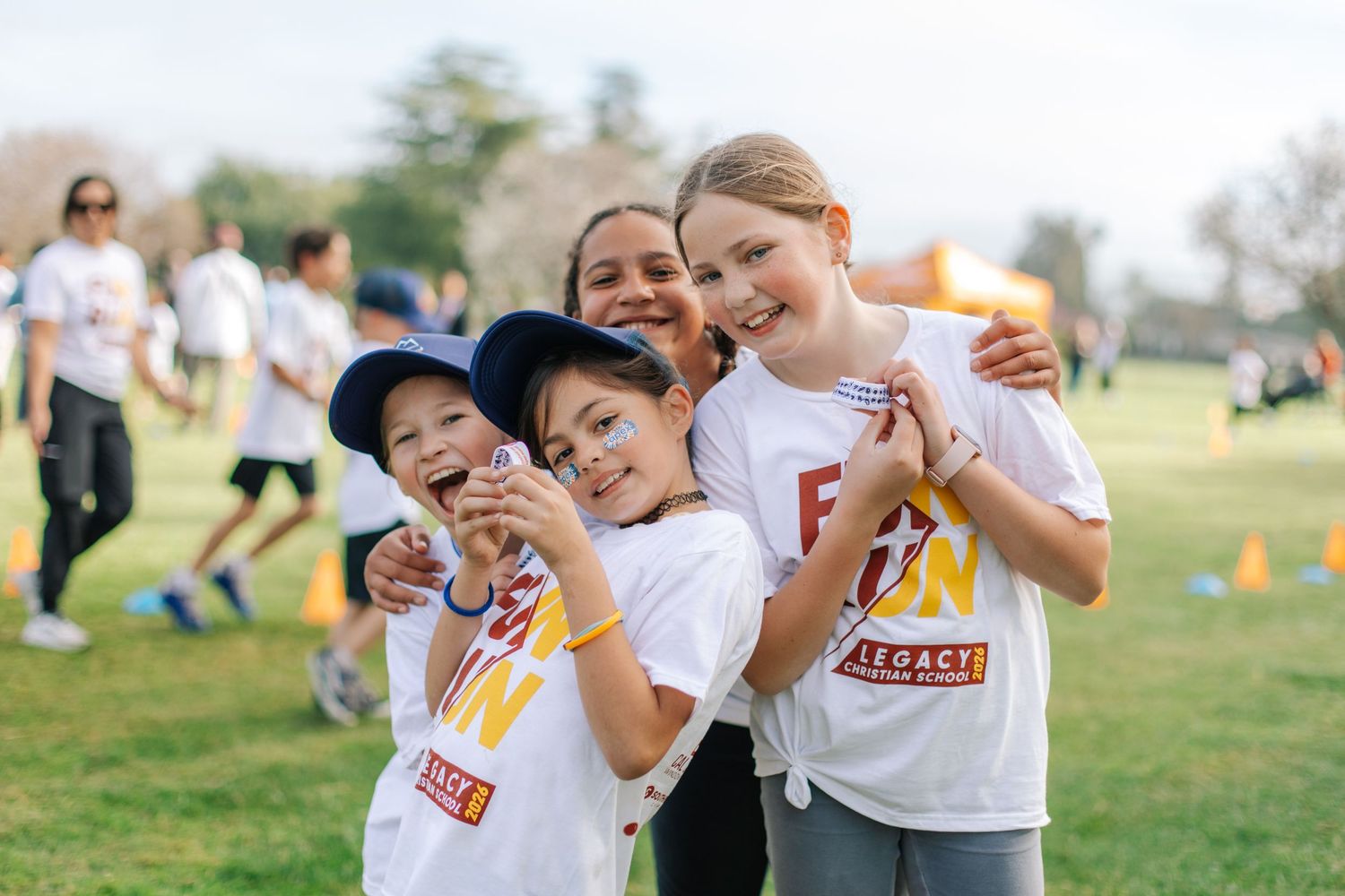 Group of smiling children in white Fun Run shirts posing together at outdoor charity event.