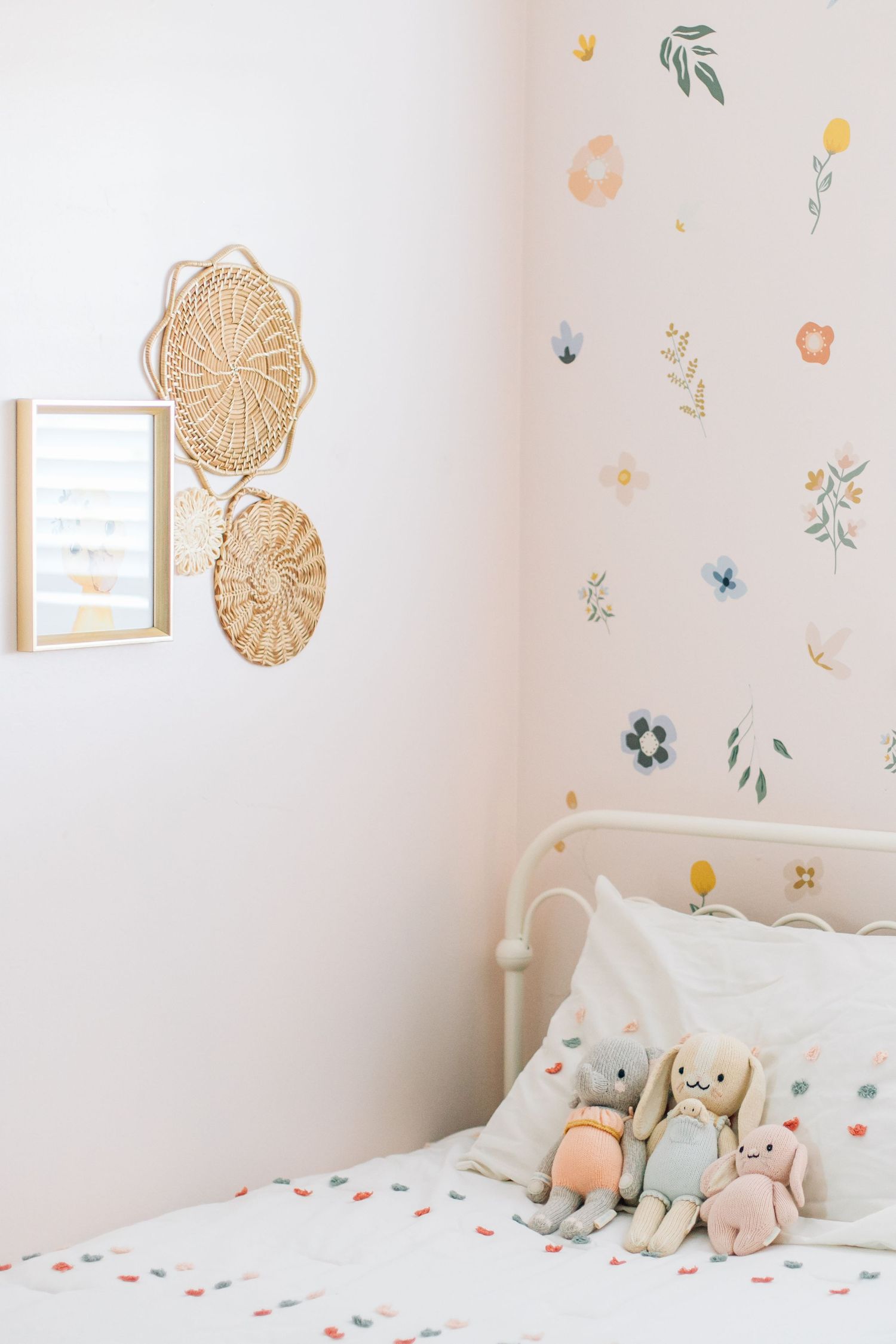 Cozy girls bedroom with floral wall decals, stuffed bunny toys, and woven wall decor.