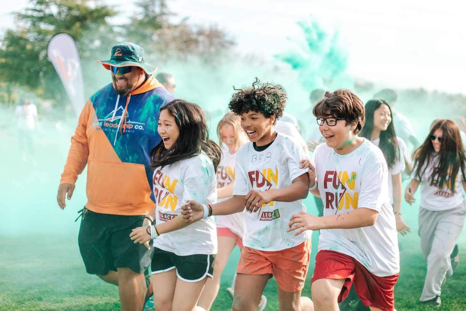 Excited children running through colorful powder clouds at a fun run outdoor event.
