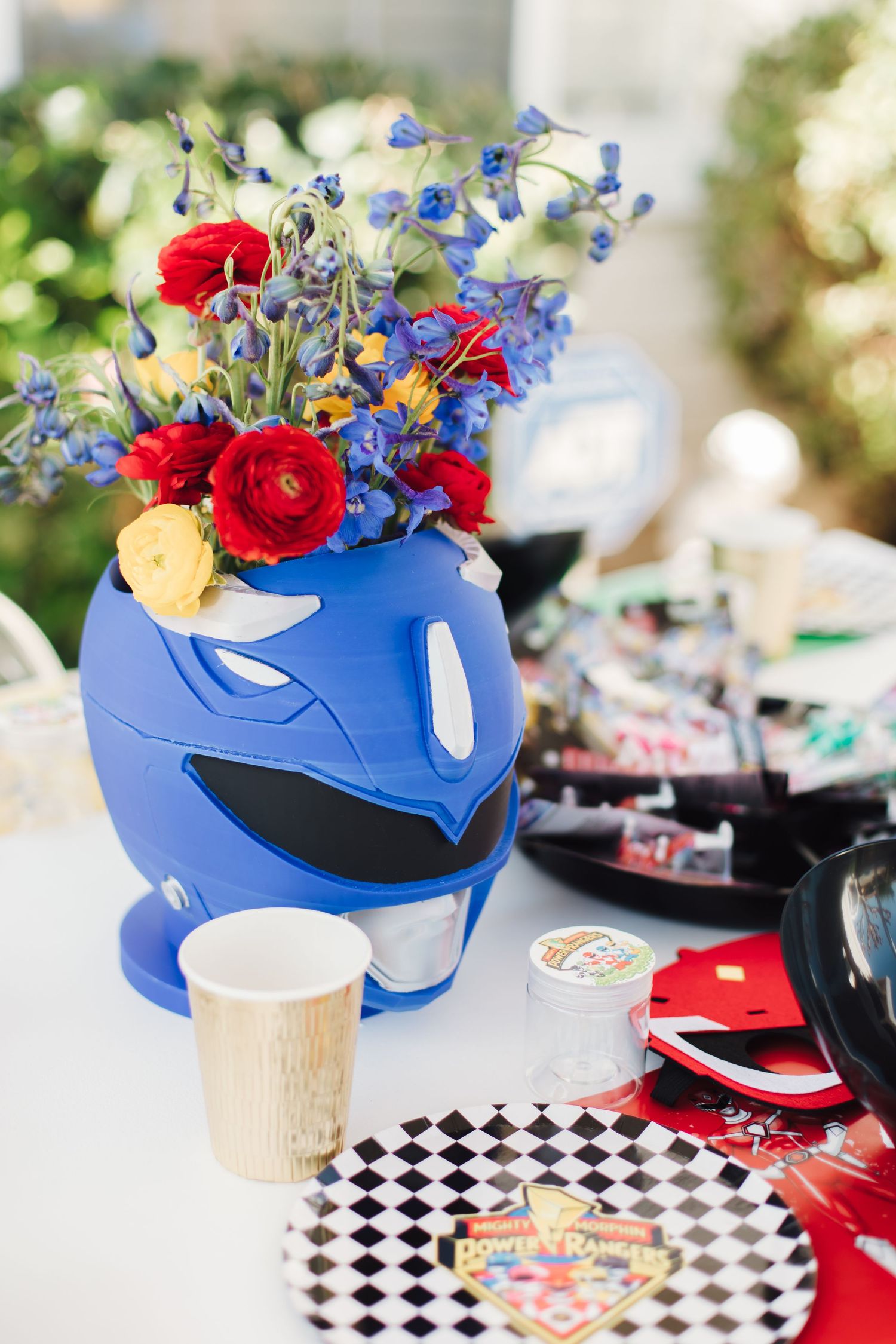 Blue Power Rangers helmet vase with colorful floral arrangement as party table centerpiece.