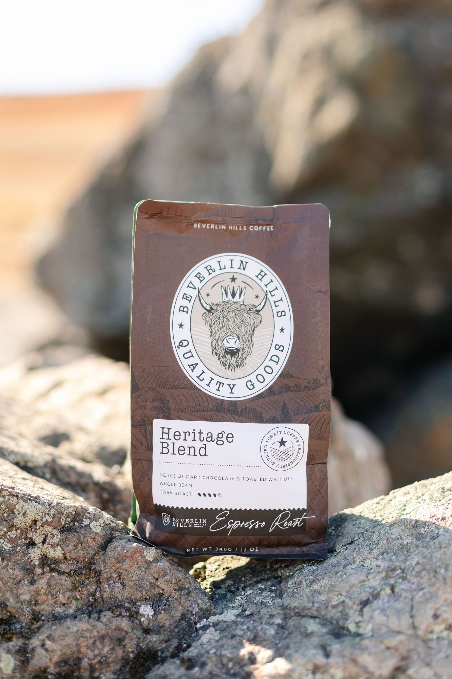 Beverlin Hills Quality Goods Heritage Blend espresso roast coffee bag displayed on rocky surface.
