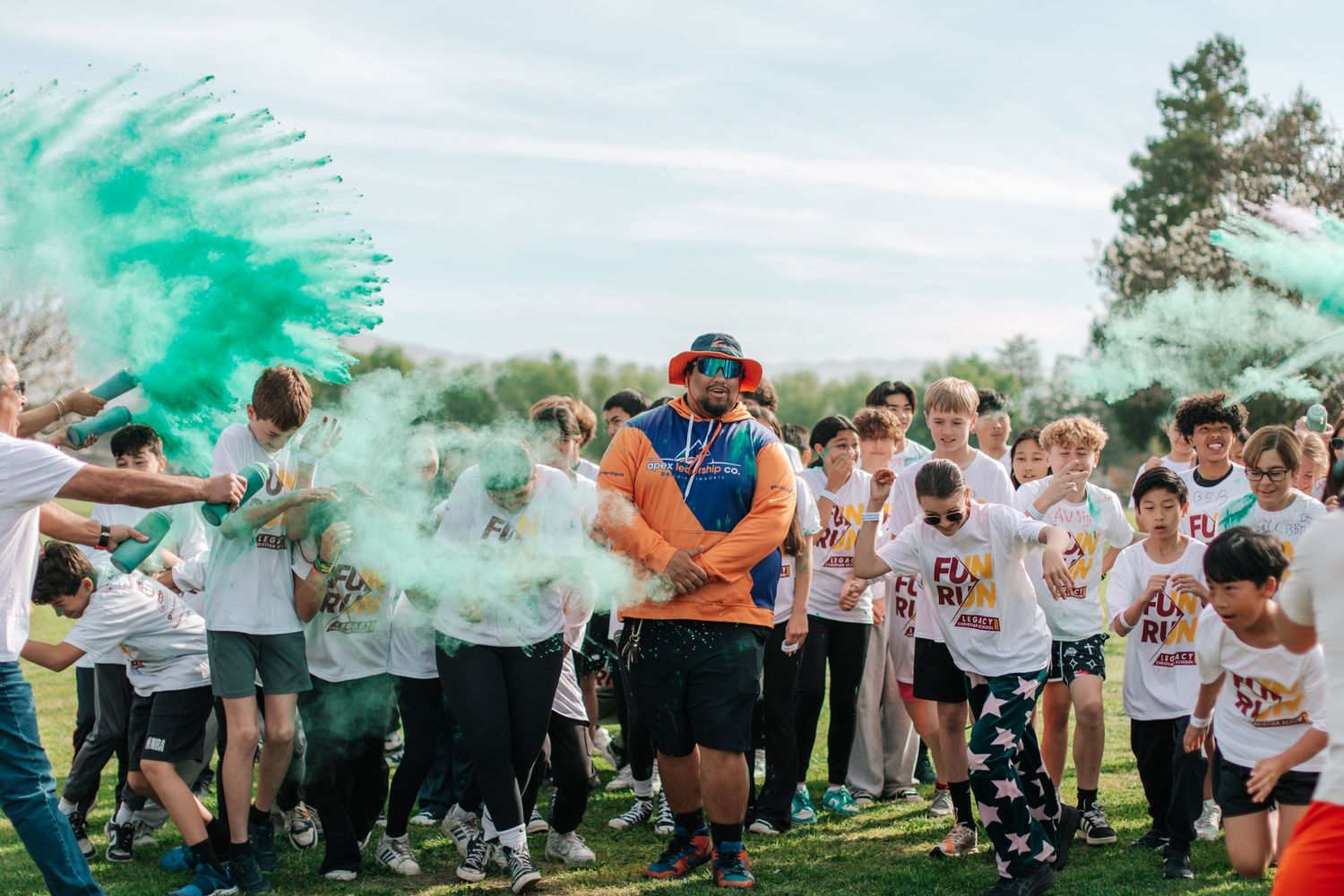 Energetic fun run event with children and adult surrounded by burst of green color powder.
