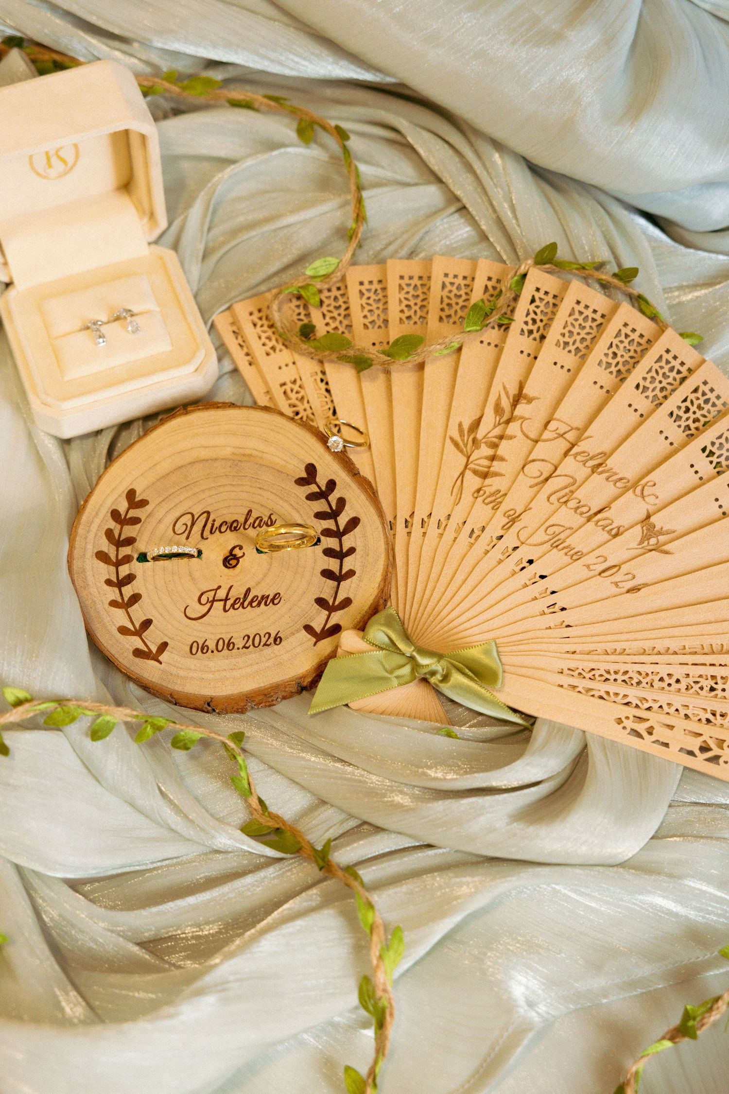 Personalized wooden wedding fan and ring box engraved with Nicolas & Helene, 06.06.2026, displayed with gold rings.