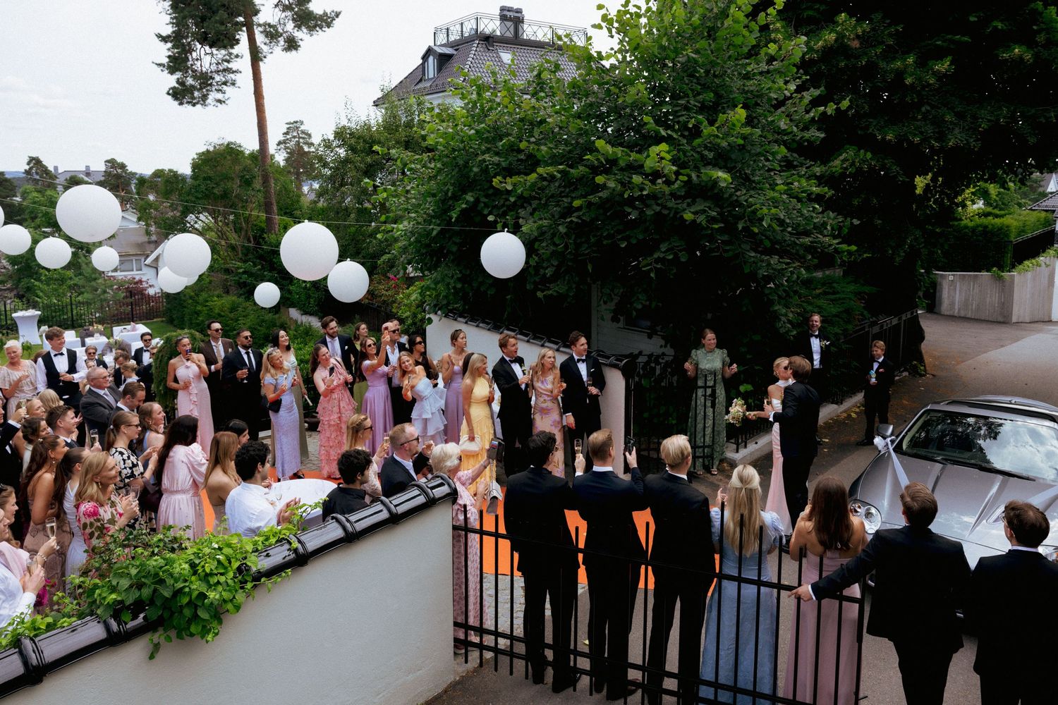 Wedding guests celebrate outdoors with white balloons at a scenic venue during evening reception.