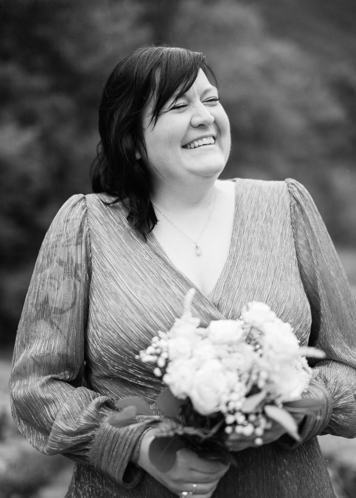 Smiling bride holds bouquet in black and white portrait photo.