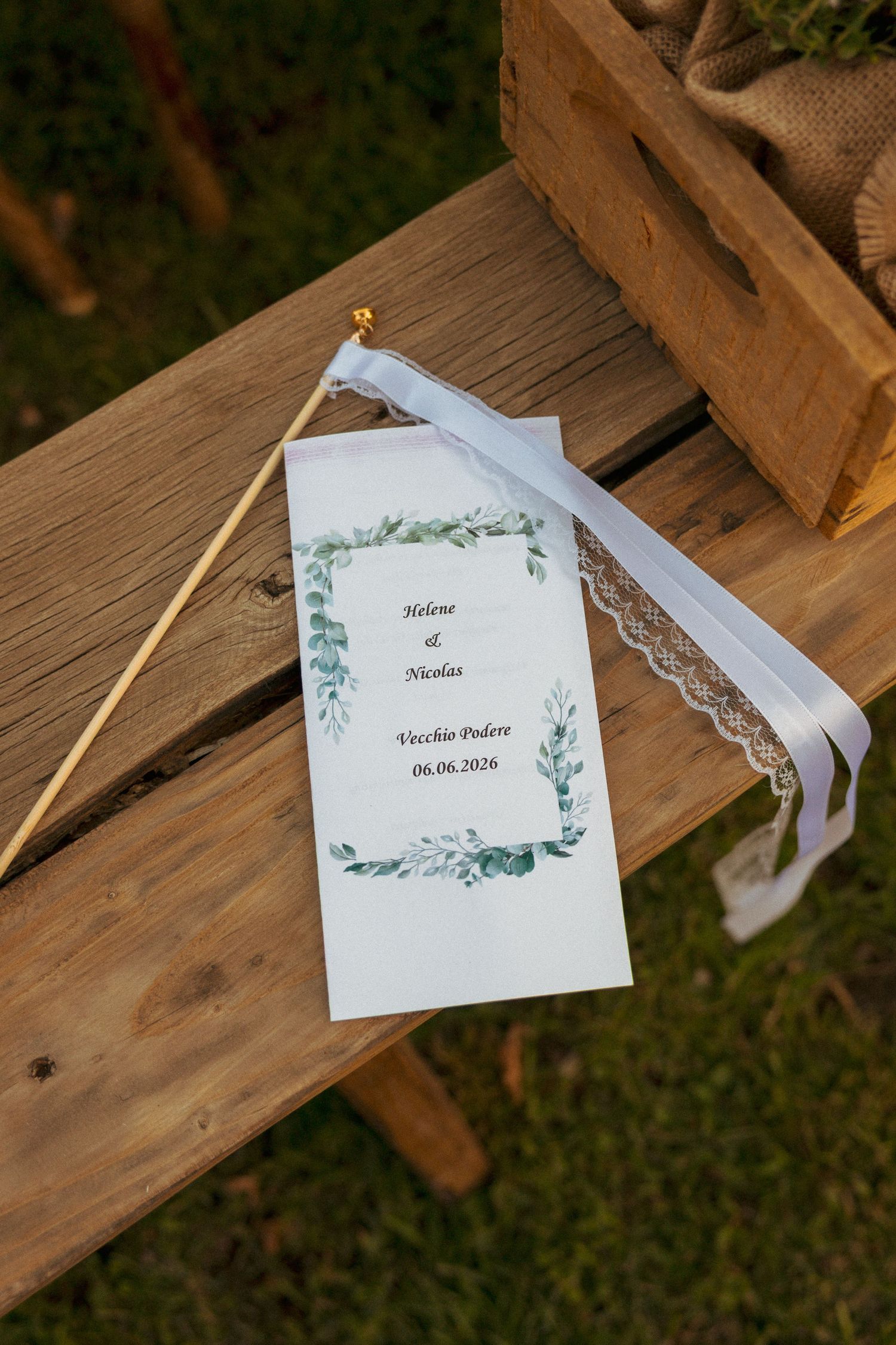 Wedding program for Helene and Nicholas at Vecchio Podere dated 06.06.2026 on wooden bench.