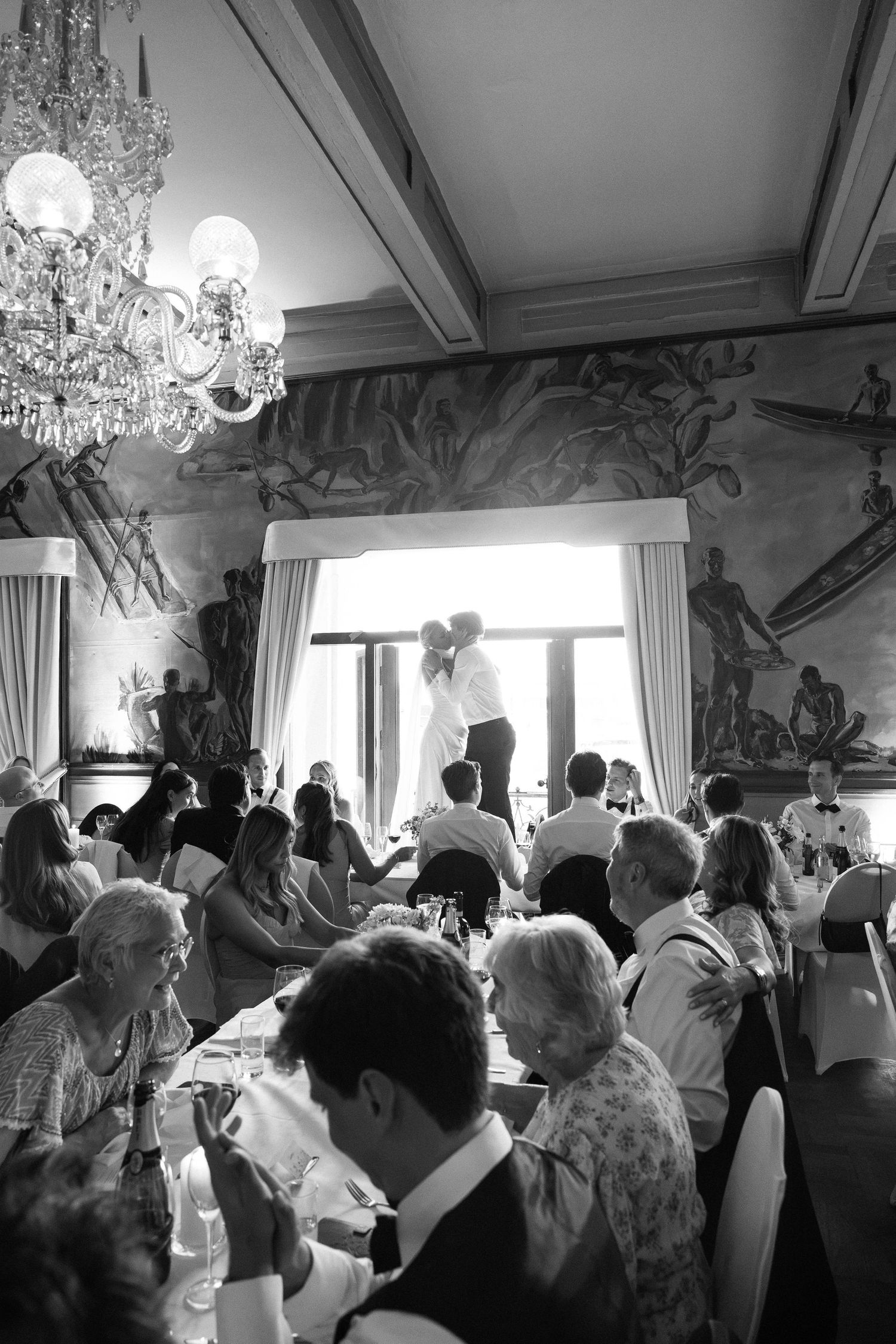 Couple shares first dance silhouetted by window in ornate frescoed reception hall.