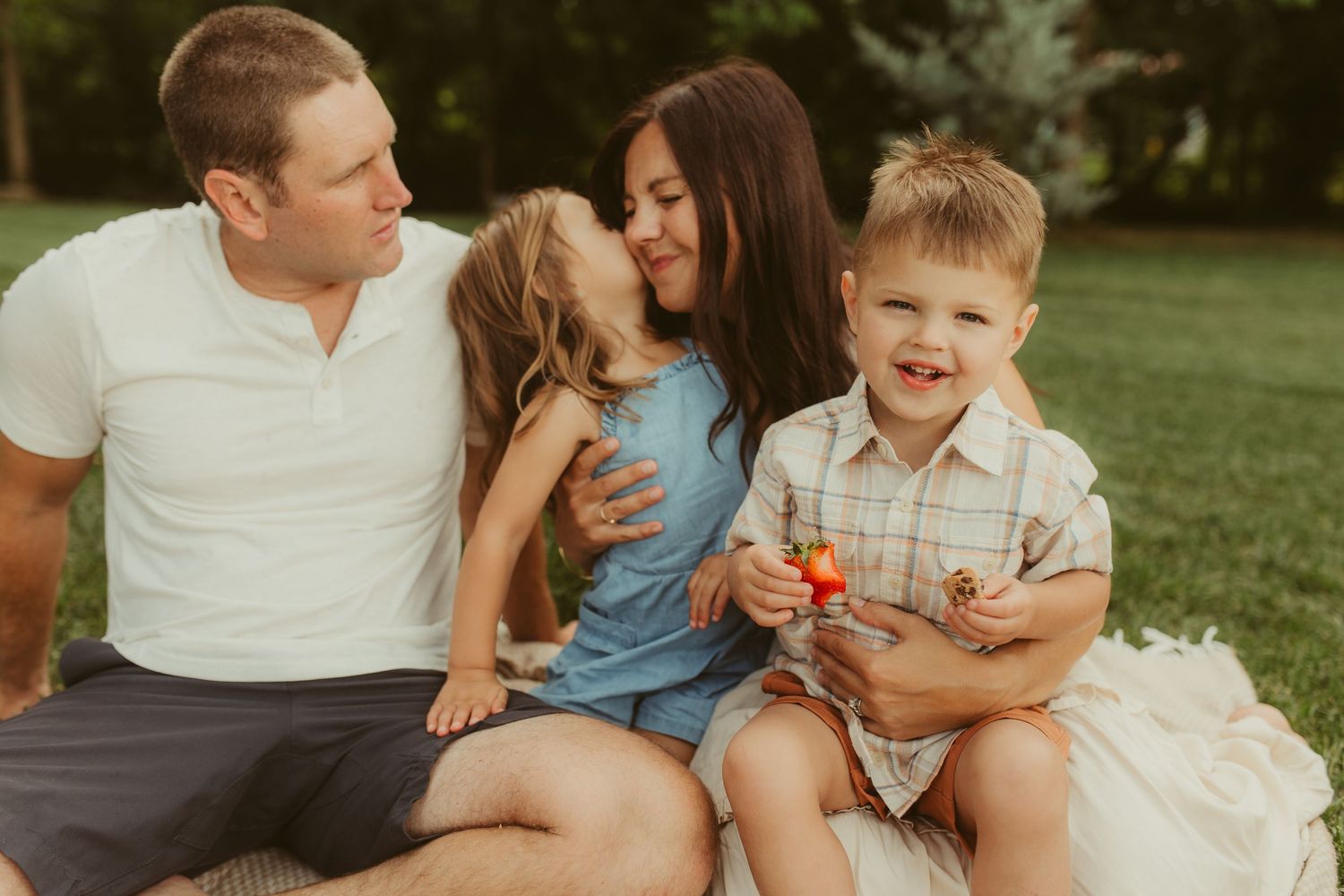 Happy family enjoying a sunny day together on grass during an outdoor photoshoot.