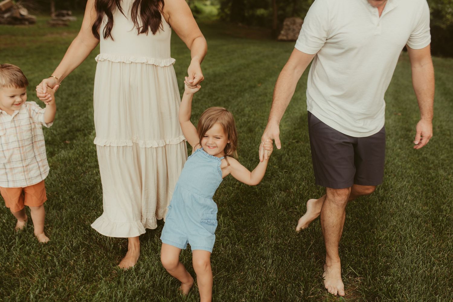 Family walking and playing together on green grass during a summer evening.